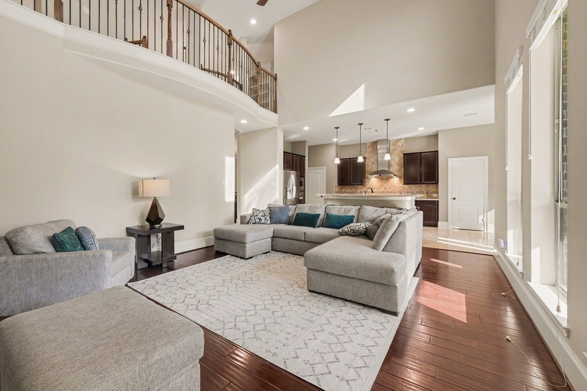6410 Archer Ranch Lane, Rosenberg, TX 77471 Impressive two-story living room with soaring ceilings, beautiful wood flooring, a fireplace, and an open layout