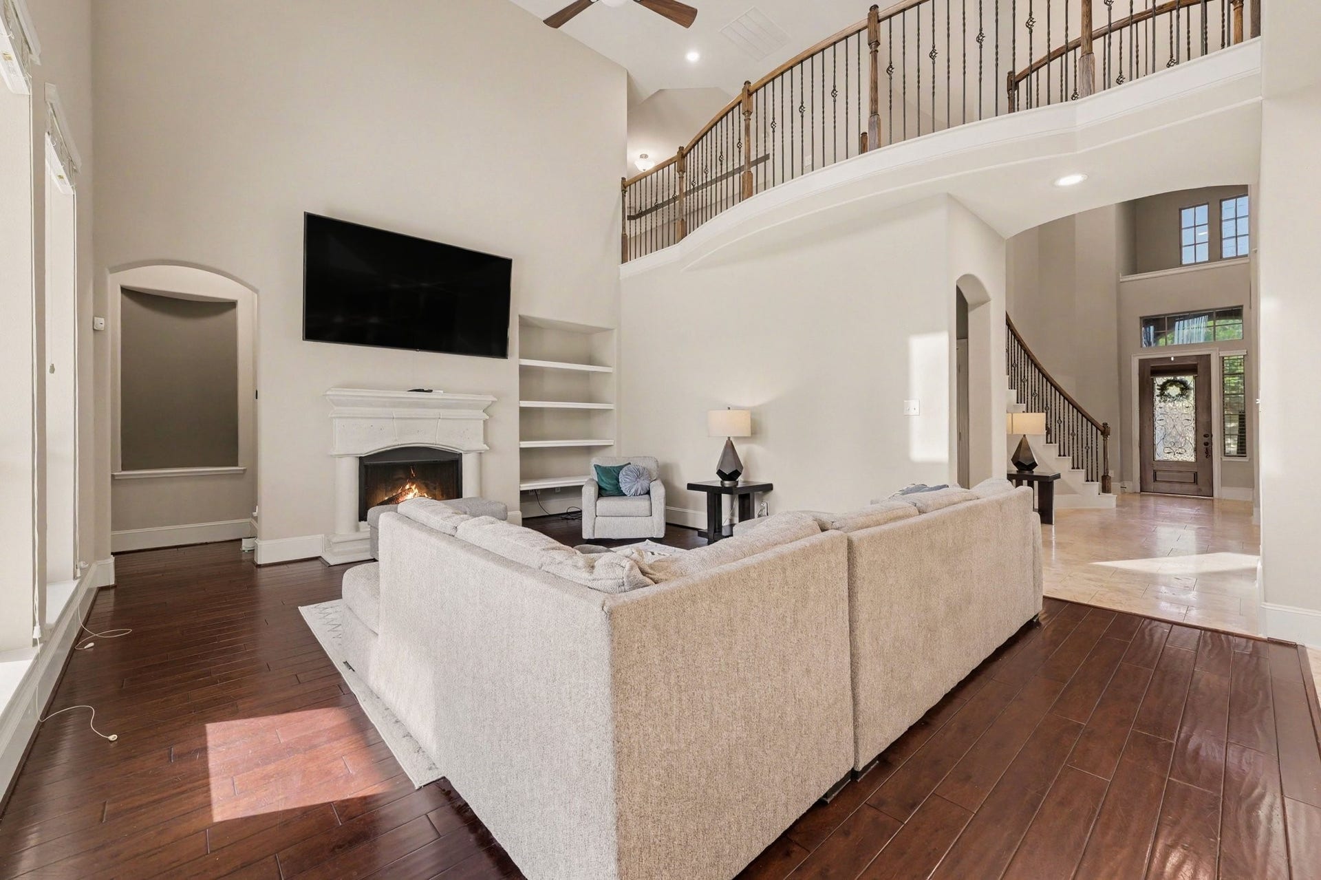 6410 Archer Ranch Lane, Rosenberg, TX 77471 Impressive two-story living room with soaring ceilings, beautiful wood flooring, a fireplace, and an open layout