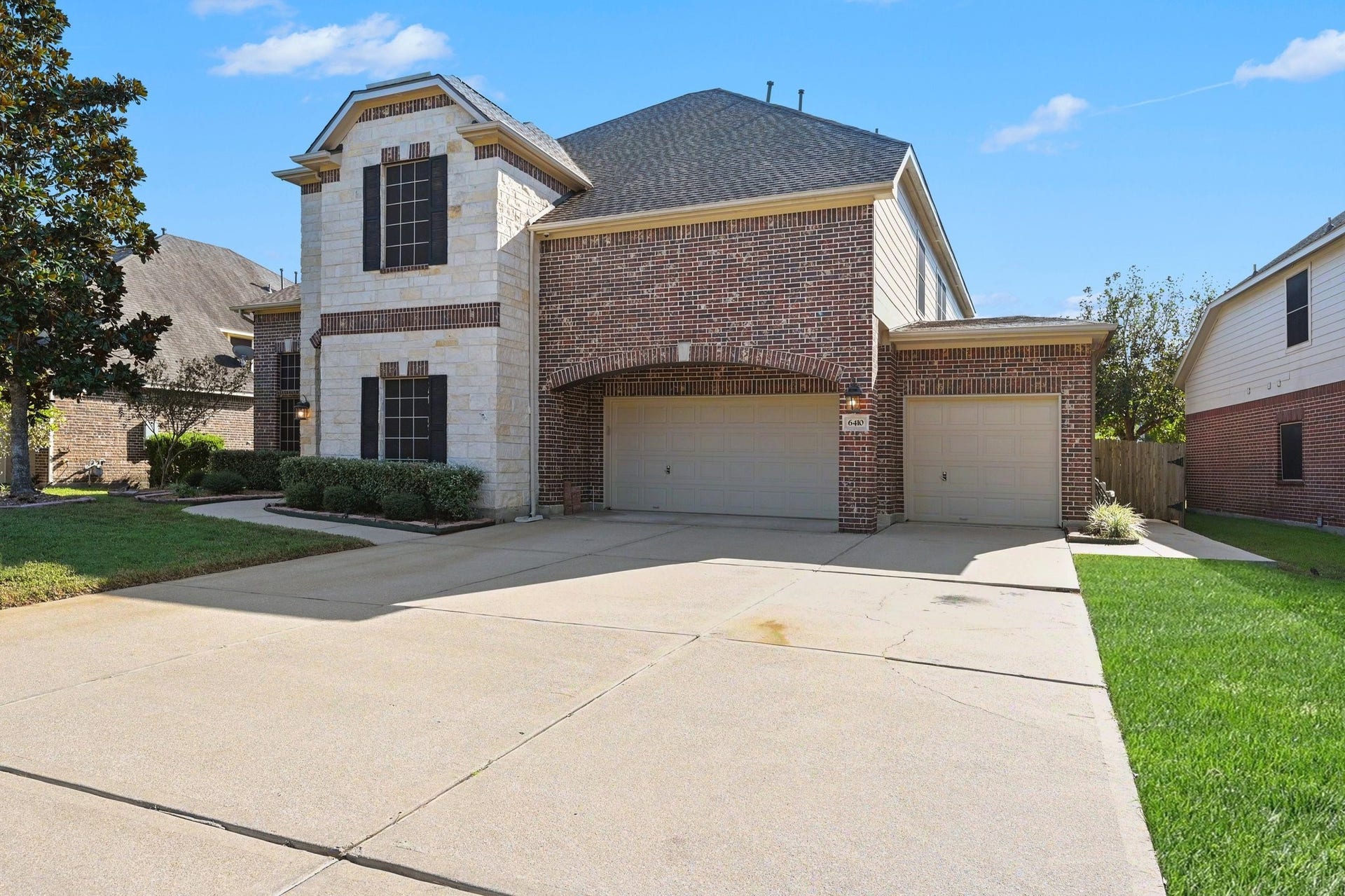 6410 Archer Ranch Lane, Rosenberg, TX 77471 Impressive two-story home with beautiful brick and stone accents, a three-car garage, and an expansive driveway.
