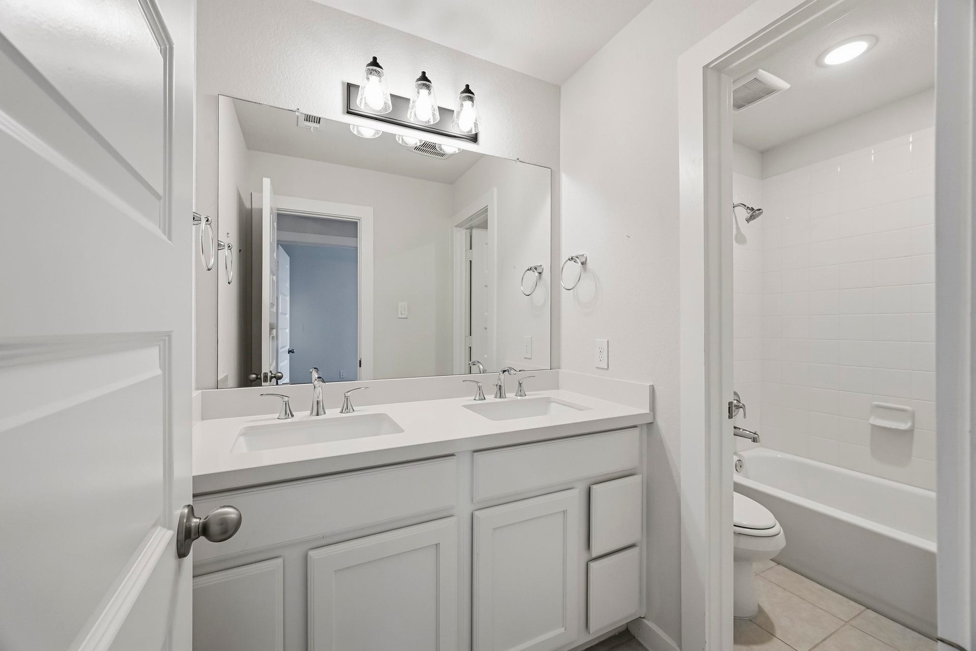 6718 Waxbill Road, Katy, TX 77493 Located just off the secondary bedrooms, this full bathroom offers additional privacy with separated vanity and shower making it easy to share and get ready. It features with white cabinets, a spacious tub and shower, dual sinks, and large mirror.