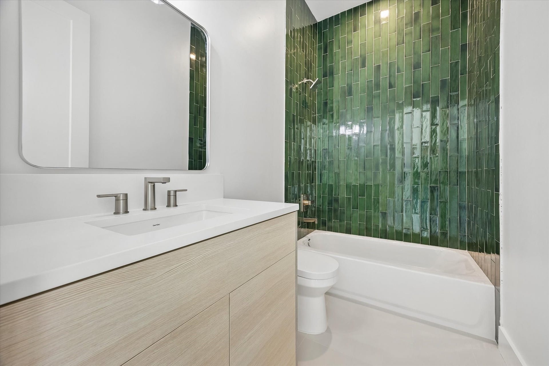 2204 Huldy Street, Houston, TX 77019 Private en-suite bathroom for the second-floor secondary bedroom features a light wood-toned vanity w/ quartz countertop, integrated sink & storage below. Tub/shower combination features decorative tile surround and built-in soap niche. Conveniently located adjacent to the bedroom's walk-in closet.