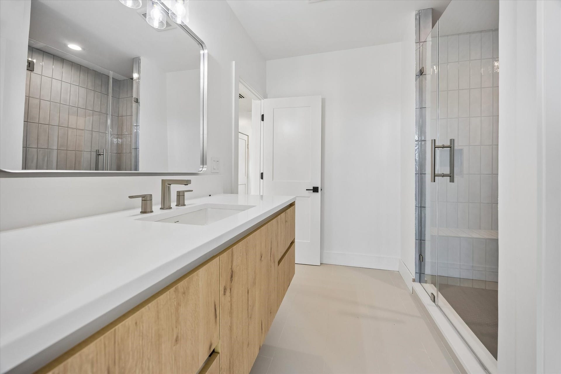 2204 Huldy Street, Houston, TX 77019 Beautiful third-floor secondary bathroom features quartz countertops, wood-toned vanity w/ storage & walk-in shower with frameless glass door, decorative tile surround & built-in soap niche. Private water closet adds convenience. Accessible from both the third-floor hallway and secondary bedroom.