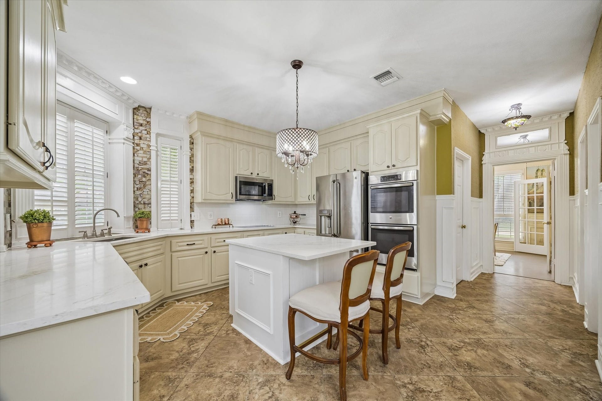 1019 Quiet Glen Court, Sugar Land, TX 77479 Elegant kitchen featuring custom cabinetry, a central island with seating, stainless steel appliances, and abundant natural light from large windows.