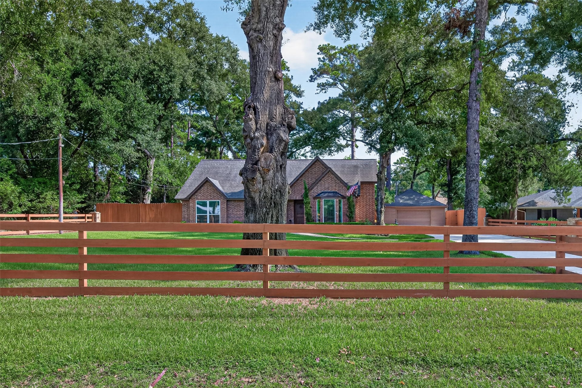 8906 Seber Drive, Tomball, TX 77375 Take in the large, tree-shaded front lawnthere is an abundance of outdoor space here, framed by mature trees and ranch style wood fencing.