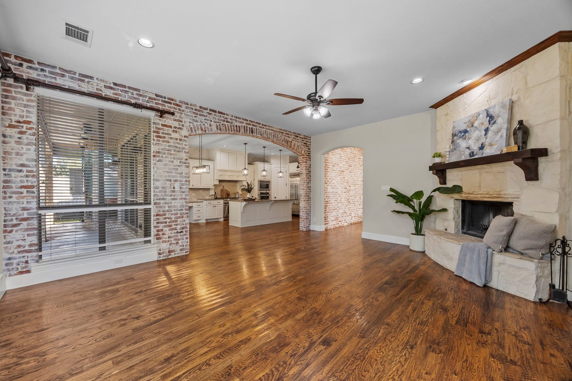 9238 Balsam Gap, Missouri City, TX 77459 Spacious family room featuring rich hardwood floors, a stunning floor to ceiling stone fireplace, and beautiful brick accent walls with an arched opening to the kitchen. A warm, inviting space perfect for everyday living and entertaining.