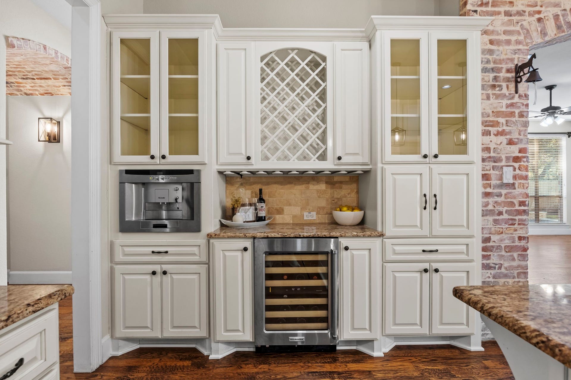 9238 Balsam Gap, Missouri City, TX 77459 Beautifully designed beverage station featuring custom white cabinetry, glass front display cabinets, decorative wine storage, granite countertops, a built-in wine refrigerator, and integrated coffee machine. A perfect space for entertaining and keeping your favorite beverages close at hand