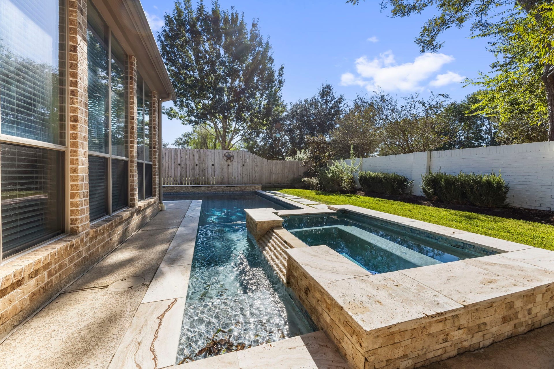 9238 Balsam Gap, Missouri City, TX 77459 Beautifully designed pool with an elevated spa, cascading water feature, and elegant stone coping. Surrounded by mature trees and lush landscaping, this private backyard retreat offers the perfect setting to cool off, unwind, and enjoy the outdoors.