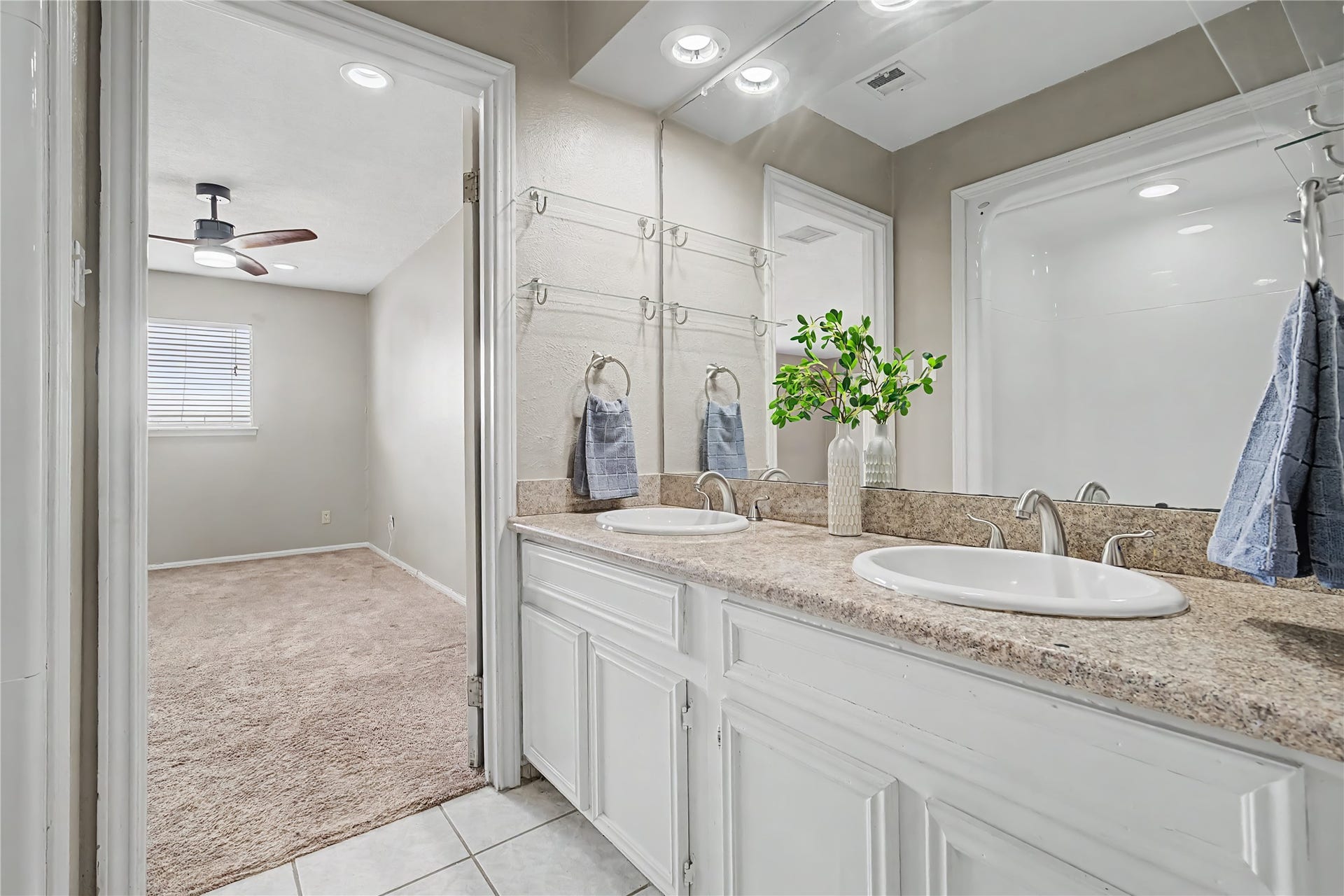 The primary bathroom features double-sink vanity with generous counter space, large mirror, and tile flooring.