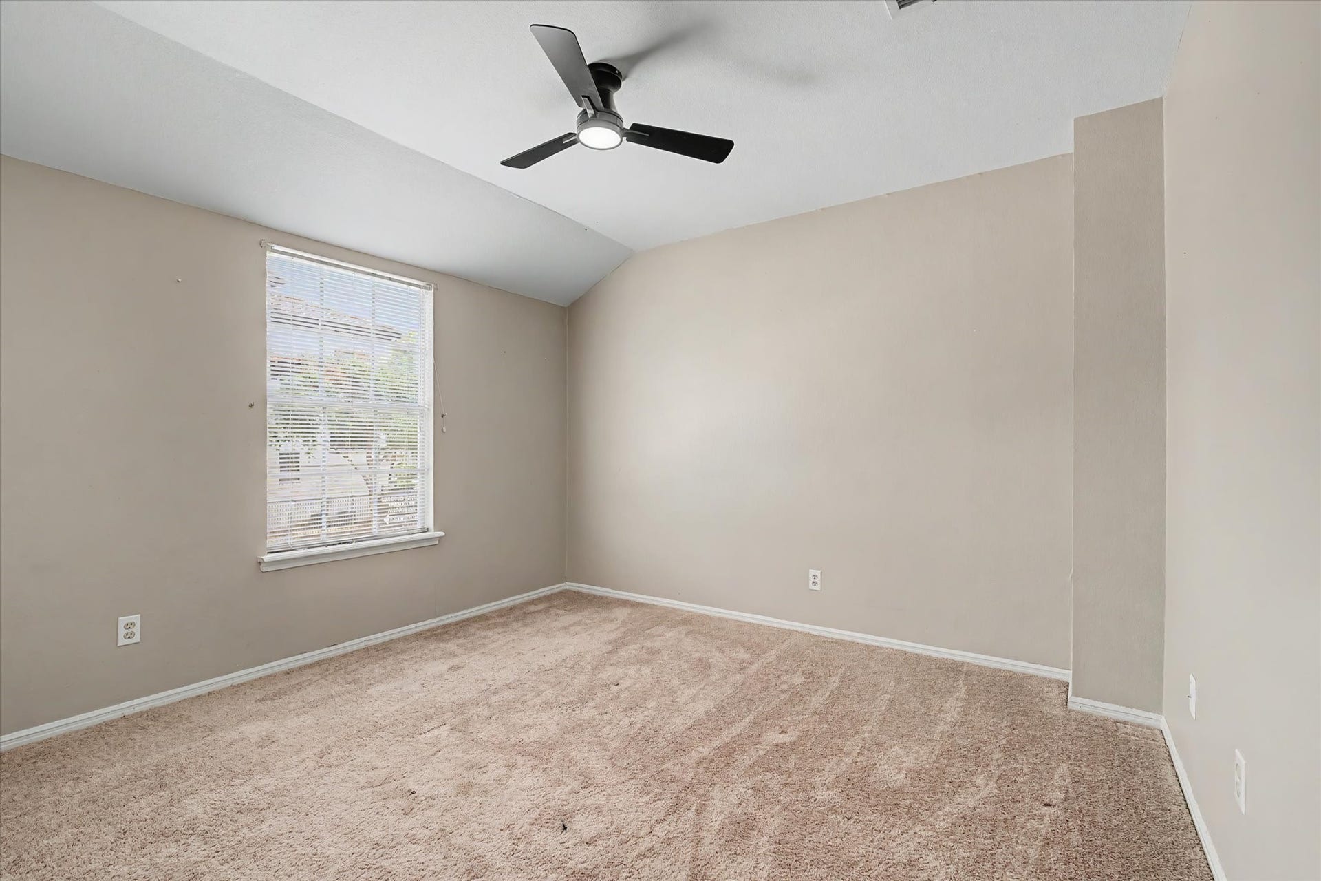 Spacious bedroom with carpet flooring, ceiling fan, and natural light.