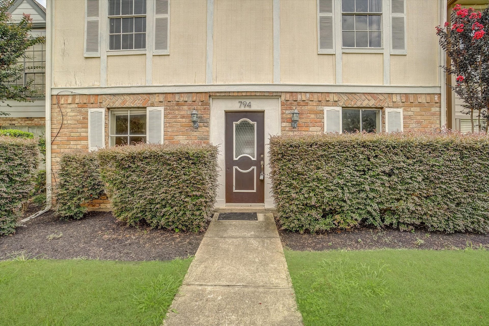 Closer view of the front entrance showcasing the brick exterior, covered entry, and surrounding landscaping.