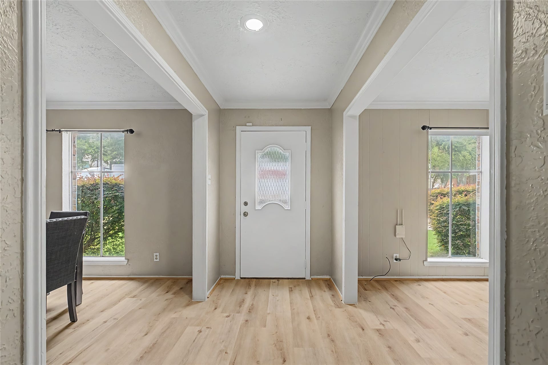 Bright entryway with updated flooring, crown molding, and openings to adjoining rooms.