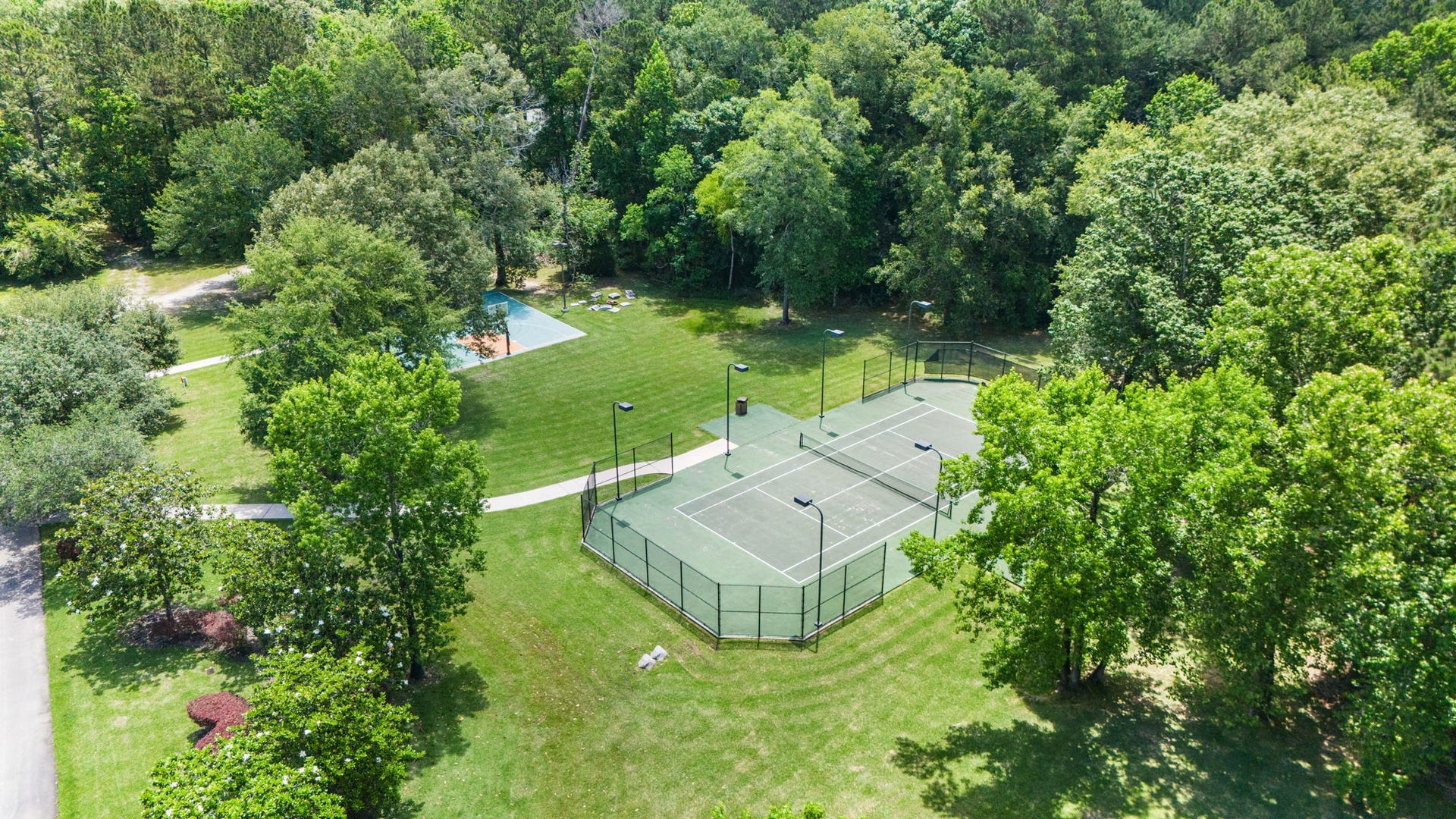 29310 Martelly Way, Huffman, TX 77336 Designed for recreation and entertaining alike, the estate features a private tennis court alongside a full basketball court, all surrounded by lush, park-like grounds. *Pictured area is part of a separate sale, but can be purchased together. Inquire for details