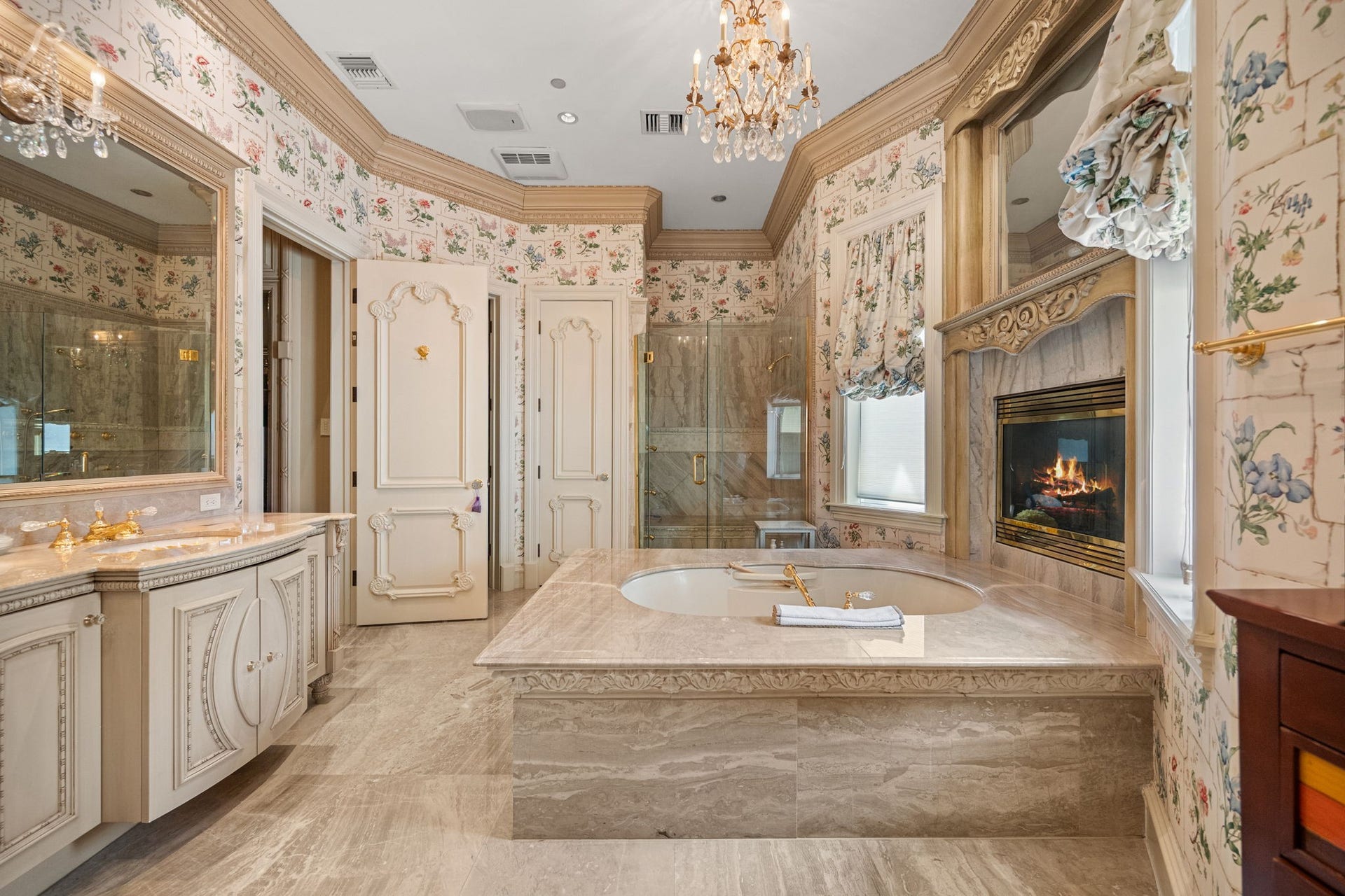 29310 Martelly Way, Huffman, TX 77336 A true spa retreat, the secondary primary bath features a carved stone soaking tub, marble fireplace, crystal chandelier, and exquisite custom millwork, creating an atmosphere of timeless elegance.