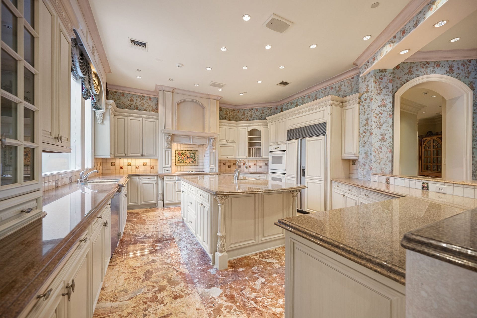 29310 Martelly Way, Huffman, TX 77336 The gourmet kitchen blends timeless elegance with professional functionality, featuring handcrafted custom cabinetry, expansive stone countertops, an oversized center island, premium built-in appliances, decorative range hood, and abundant workspace designed for effortless entertaining.