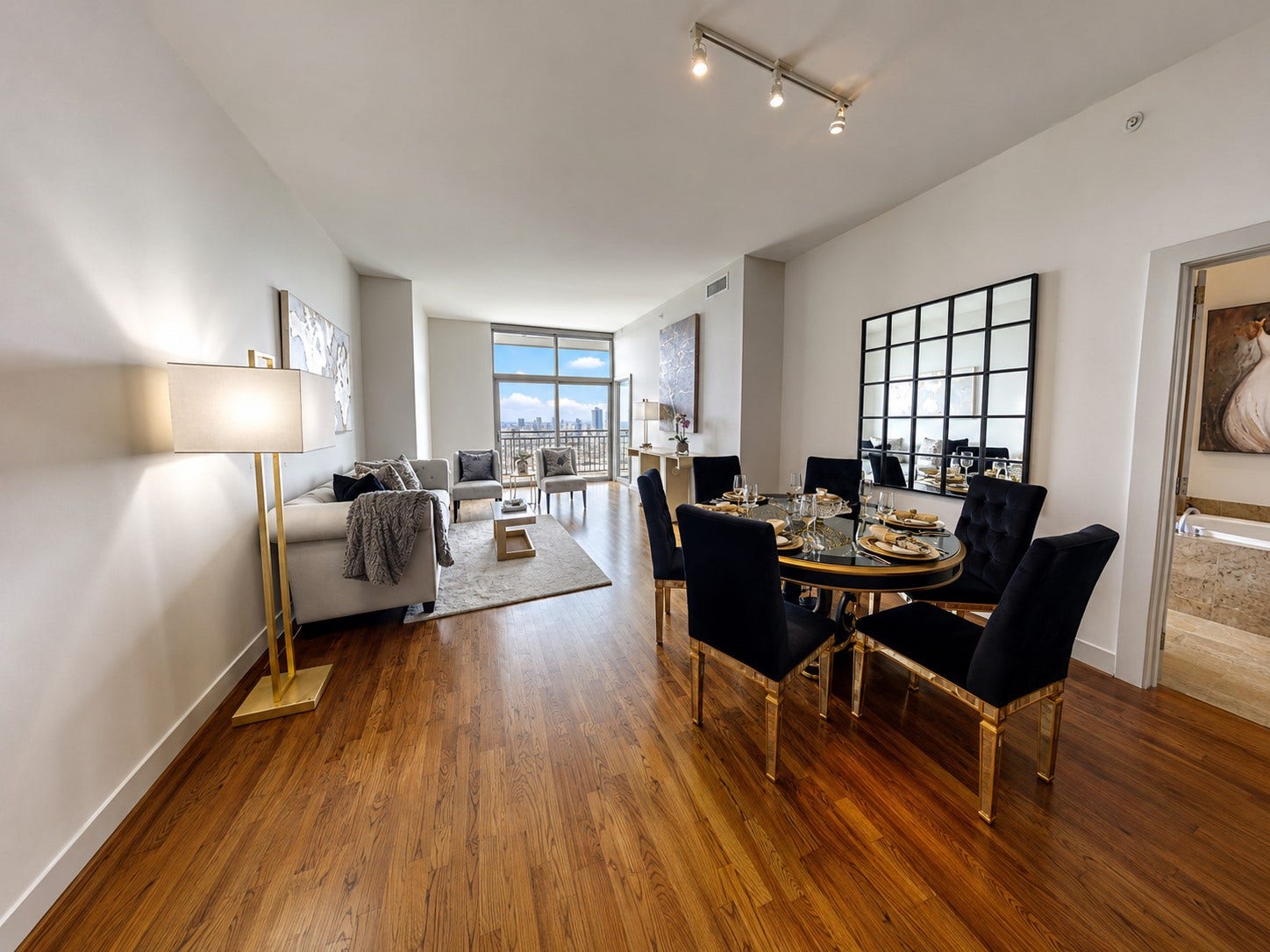 1400 McKinney Street, #2401, Houston, TX 77010 Light-filled living and dining area with warm hardwood floors, sophisticated finishes and expansive windows showcasing elevated city views.