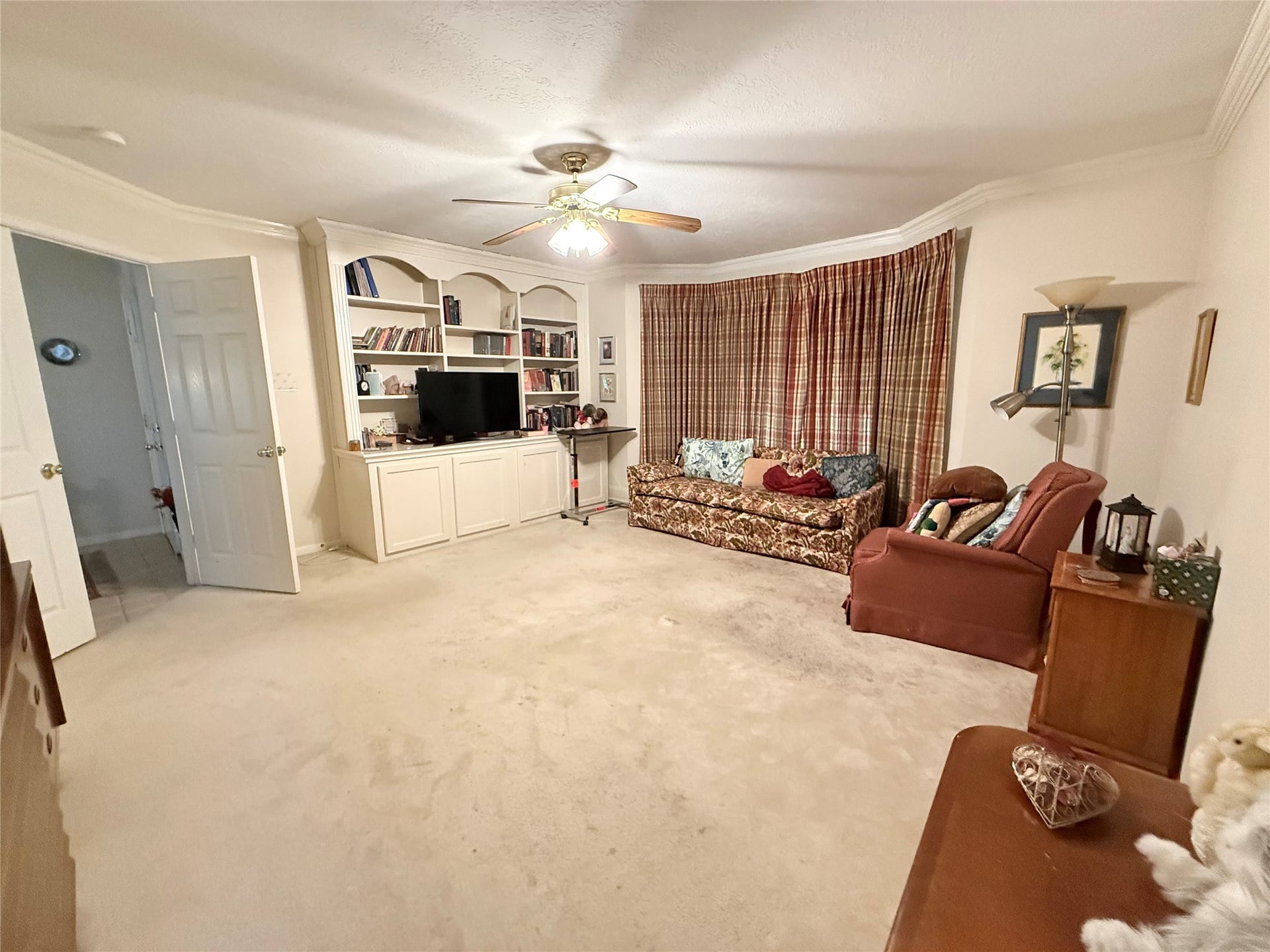 1600 Carriage Run W, Conroe, TX 77384 A Spacious Primary Suite with Custom Charm! Double doors welcome you into this generously sized primary suite, where beautiful built-in bookshelves add character, architectural interest, and wonderful space to display treasured books, photographs, collectibles, and your TV. A sunny bay window fills the room with natural light and offers the perfect spot for a cozy reading chair. Crown molding and a lighted ceiling fan complete this inviting space, with plenty of room to relax and unwind!