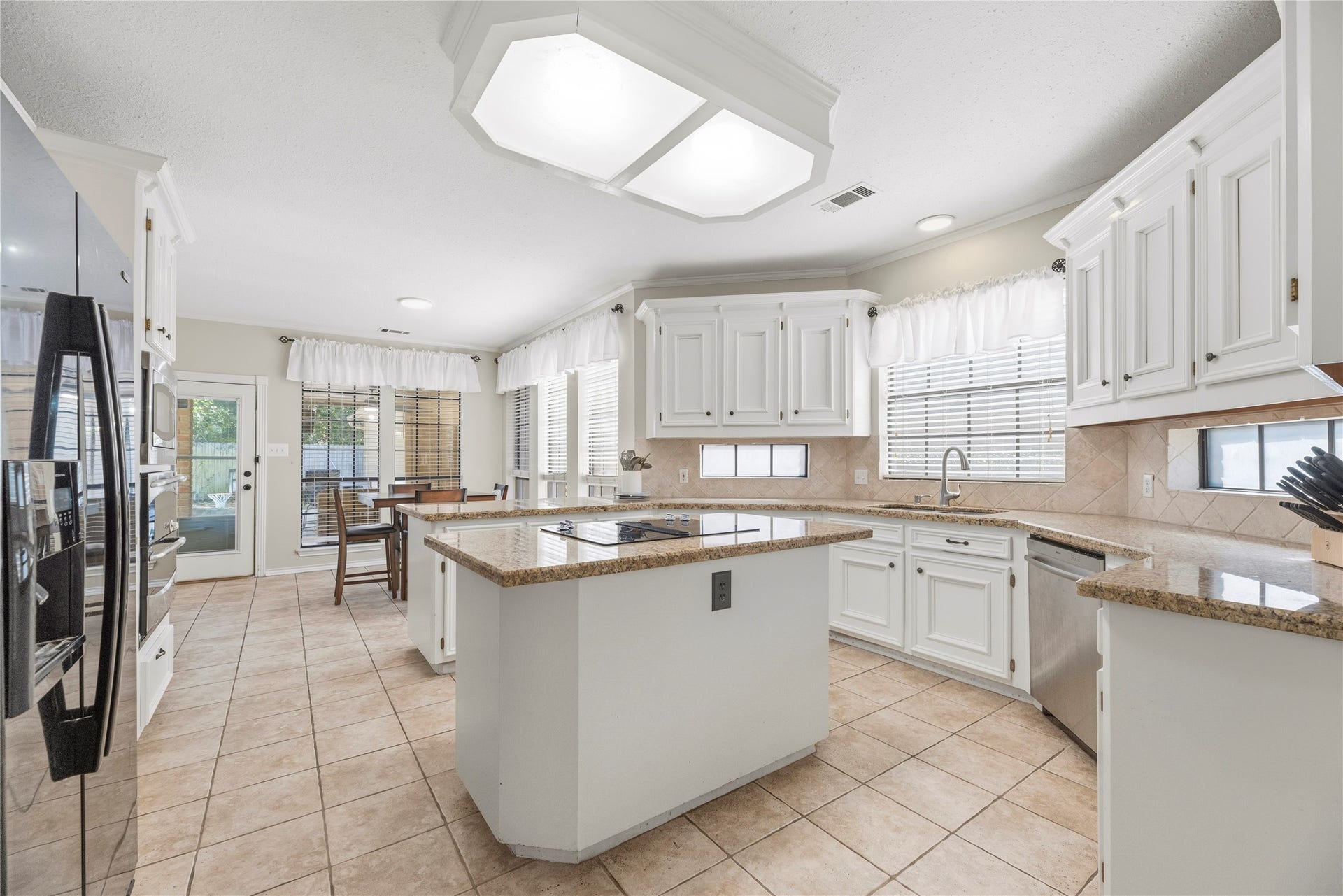 5823 Ashmere Lane, Spring, TX 77379 The heart of the home is this spacious, inviting kitchen featuring crisp white cabinetry, beautiful granite, countertop windows, a center island with electric cooktop and easy-care tile flooring. With plenty of room to prep, cook and gather, everything from busy weekday breakfasts to preparing your favorite family recipes becomes a chance to make lasting memories.
