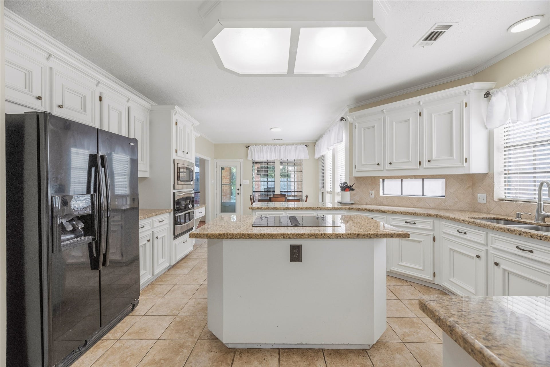 5823 Ashmere Lane, Spring, TX 77379 There's so much to love about this bright, welcoming kitchen, where a spacious center island with electric cooktop puts you right in the middle of the action. Crisp white cabinetry, granite countertops, tile backsplash and bright overhead lighting create a cheerful space where cooking feels less like a chore and more like time well spent.