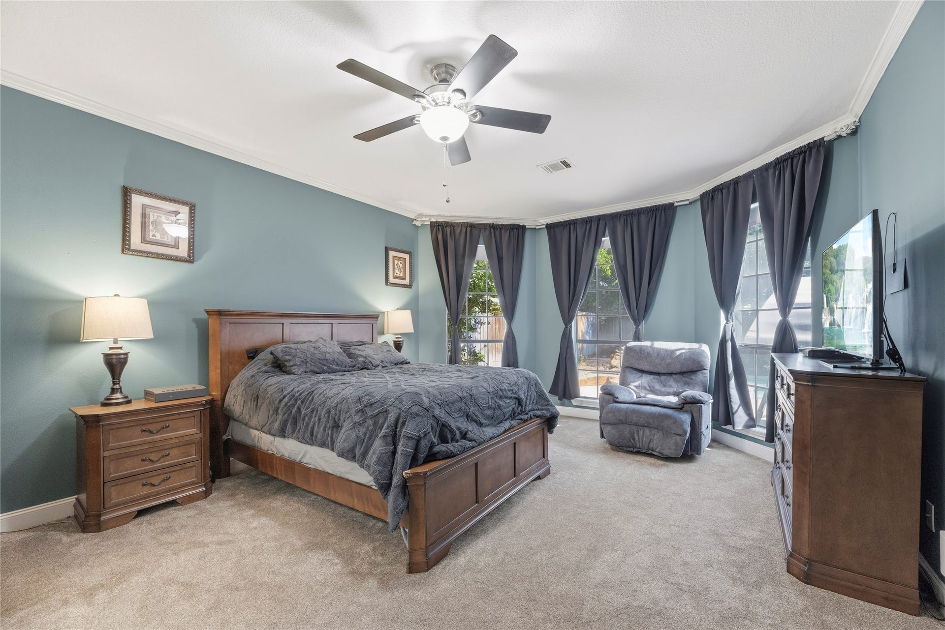 5823 Ashmere Lane, Spring, TX 77379 This spacious first-floor primary suite offers a comfortable retreat with updated carpet, designer paint, crown molding and a raised ceiling with a cooling fan. Beautiful bay windows bring in natural light and offer views of the backyard, while the roomy layout provides plenty of space for a king-size bedroom set and a cozy sitting area.