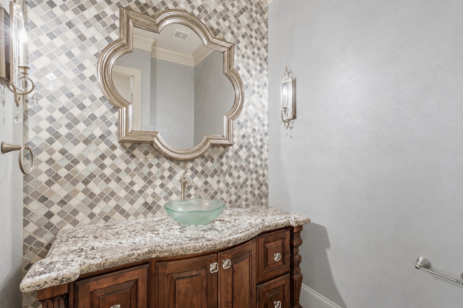 The powder room features a granite-topped vanity and a decorative arabesque tile accent wall.