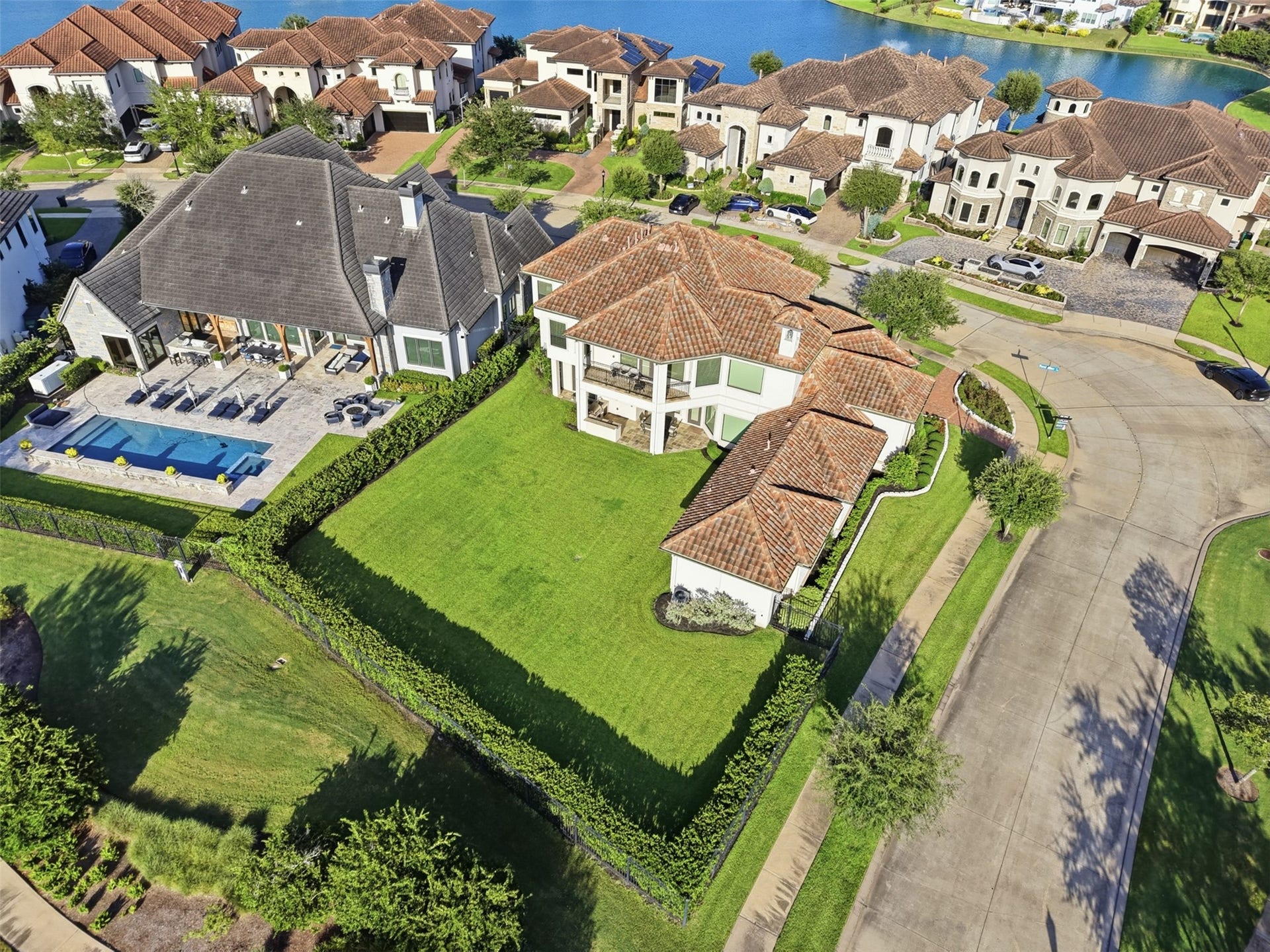 Overhead view of the sprawling lawn layout, covered patio architecture, and adjacent waterfront surroundings.