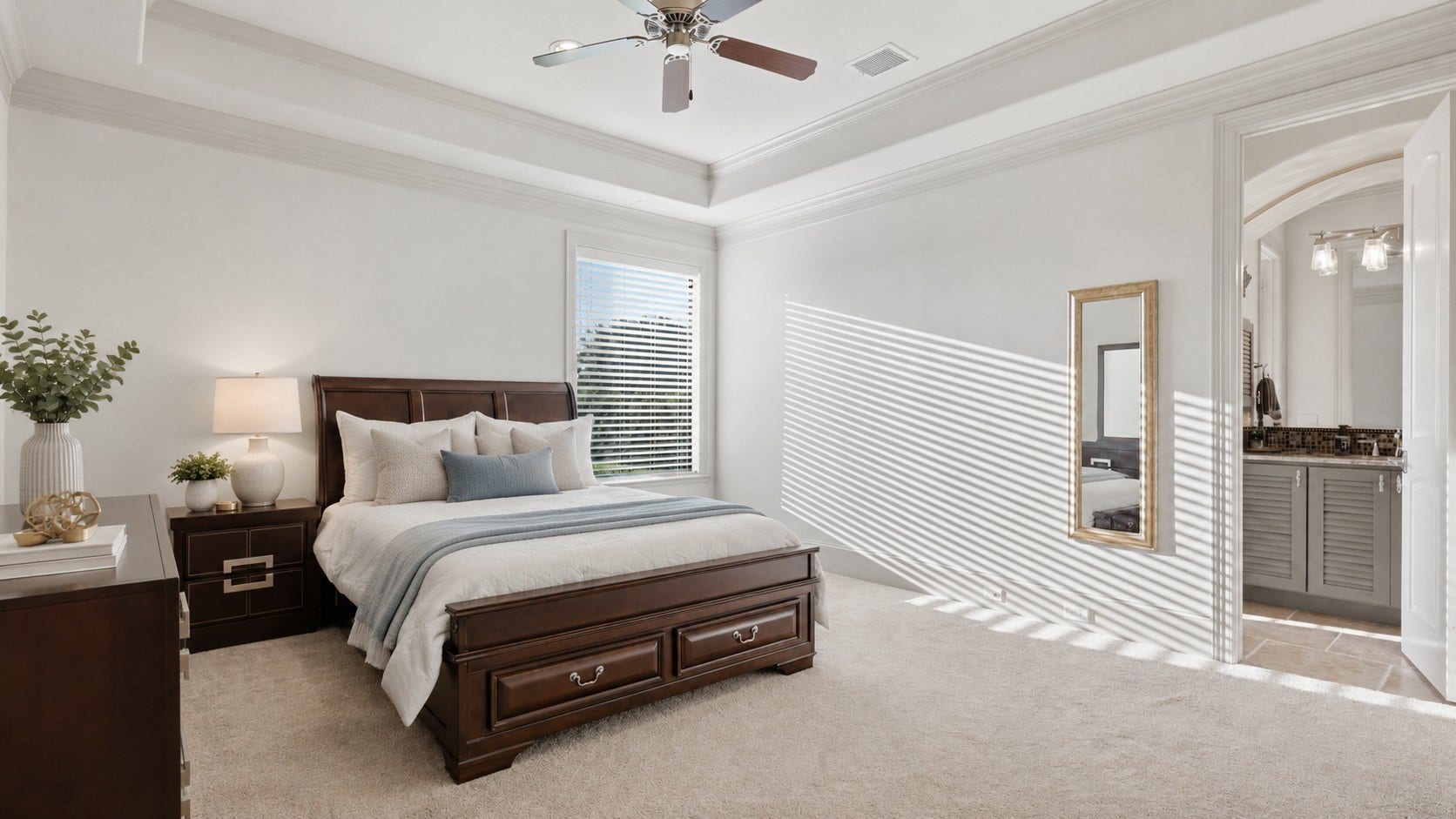 First-floor secondary bedroom with a tray ceiling, crown molding, and soft carpeting.**Virtually staged