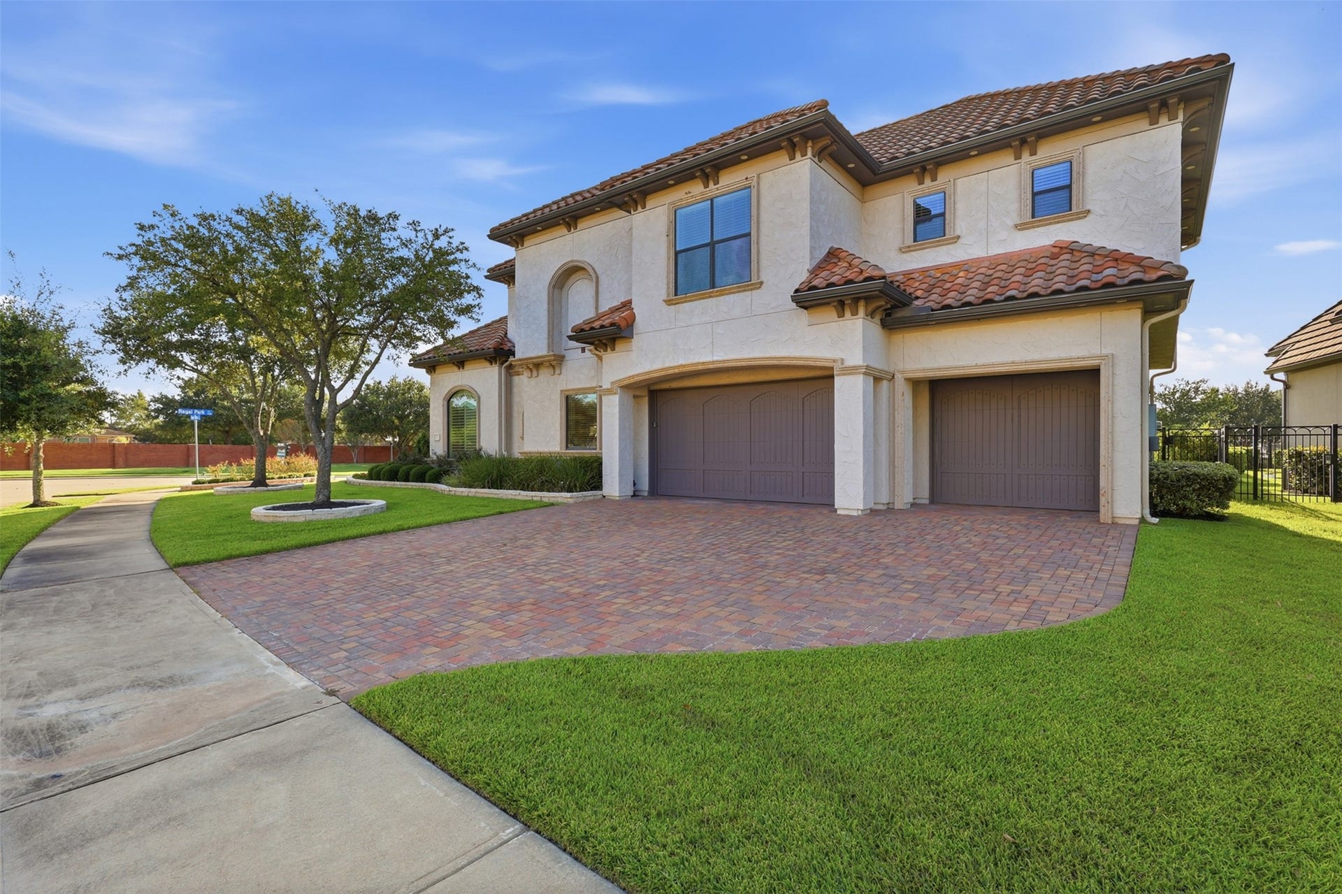 An oversized paver driveway offers seamless access to the multi-bay garage structure, complemented by stone column surrounds, recessed eave lighting, and custom exterior millwork.