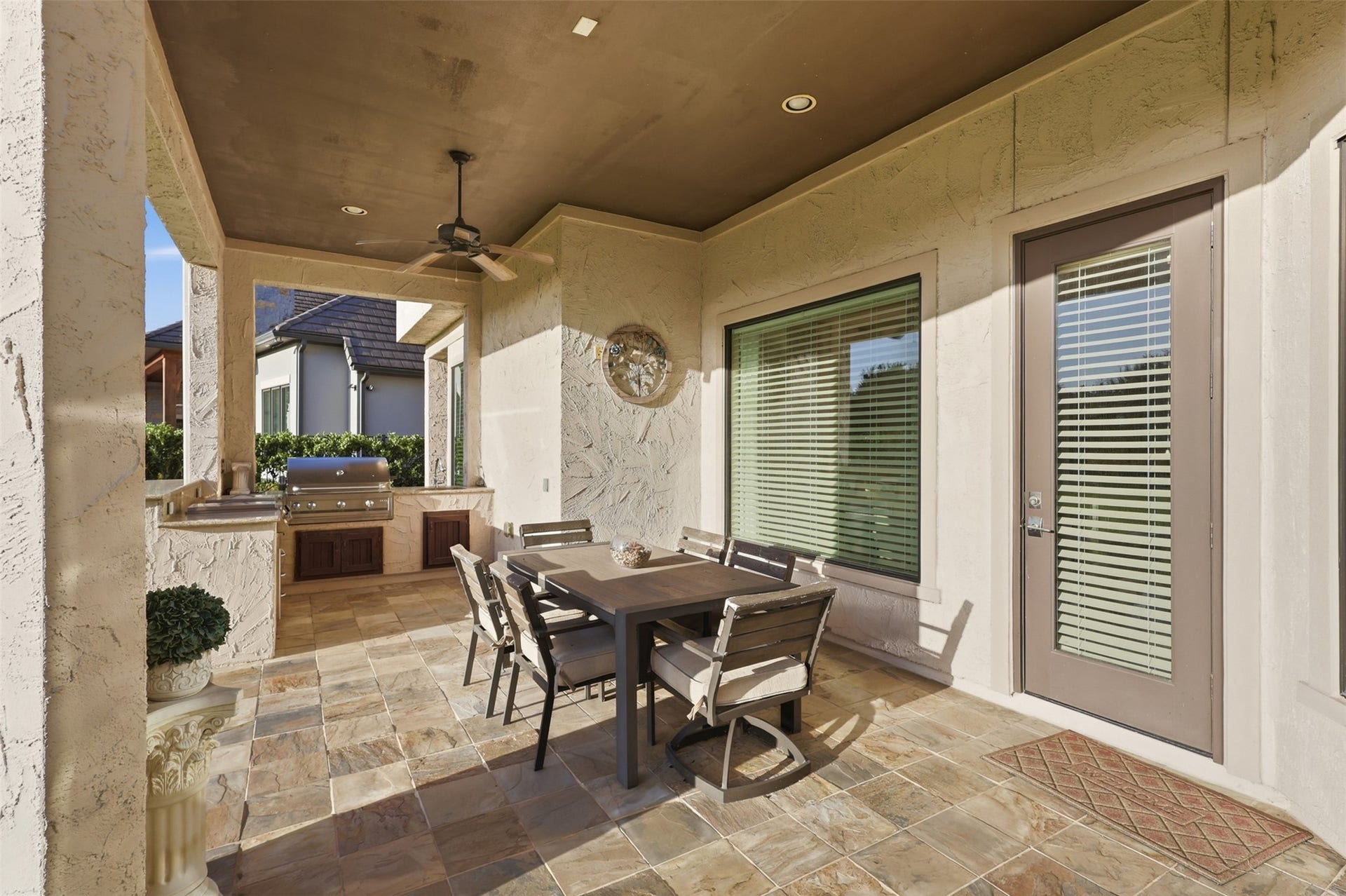Outdoor loggia outfitted with flagstone patio flooring, a built-in stone grill station, and recessed lighting.
