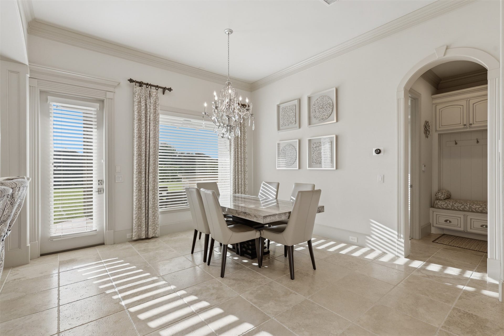 The breakfast alcove includes a glass-paneled exterior door, classic baseboard trim, and a adjacent arched entryway leading to a built-in mudroom bench.