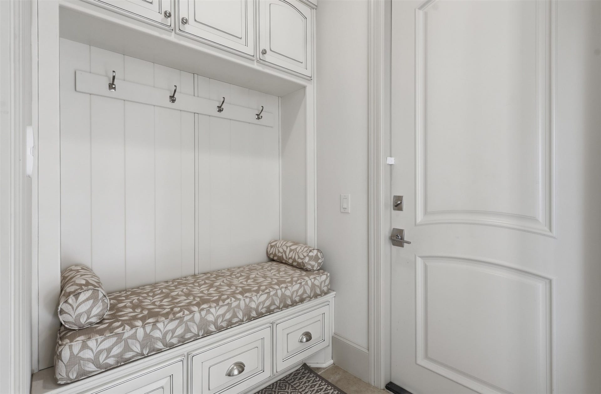 A built-in drop zone offers custom mudroom storage with upper cabinetry, hanging hooks, lower drawer units, and beadboard wall panelling.