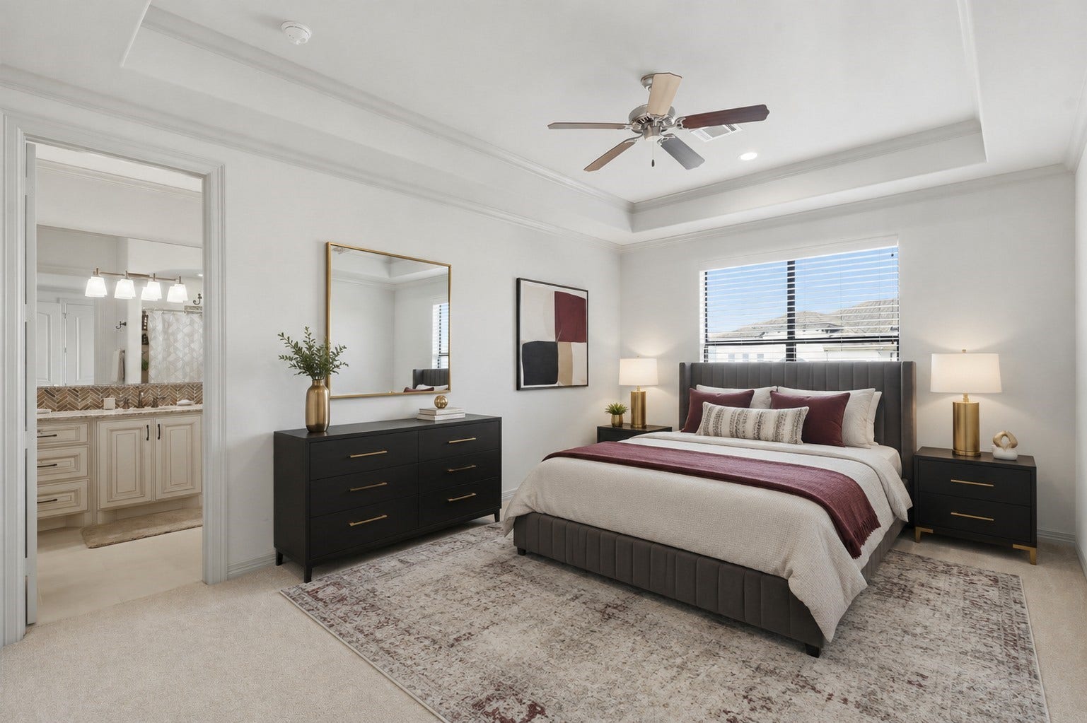 Light-filled bedroom 4 with a tray ceiling, crown molding, plush carpeting, and en-suite bath access.**Virtually staged