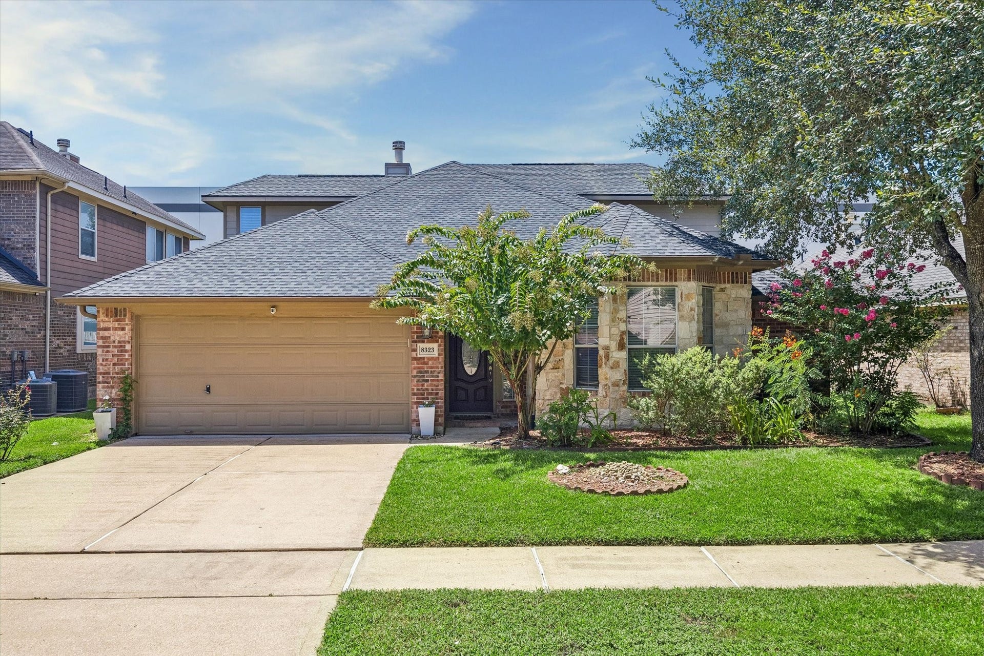 8323 Whisper Point Drive, Houston, TX 77040 Charming two-story home with a stone and brick facade, featuring a well-maintained front yard and a spacious two-car garage.