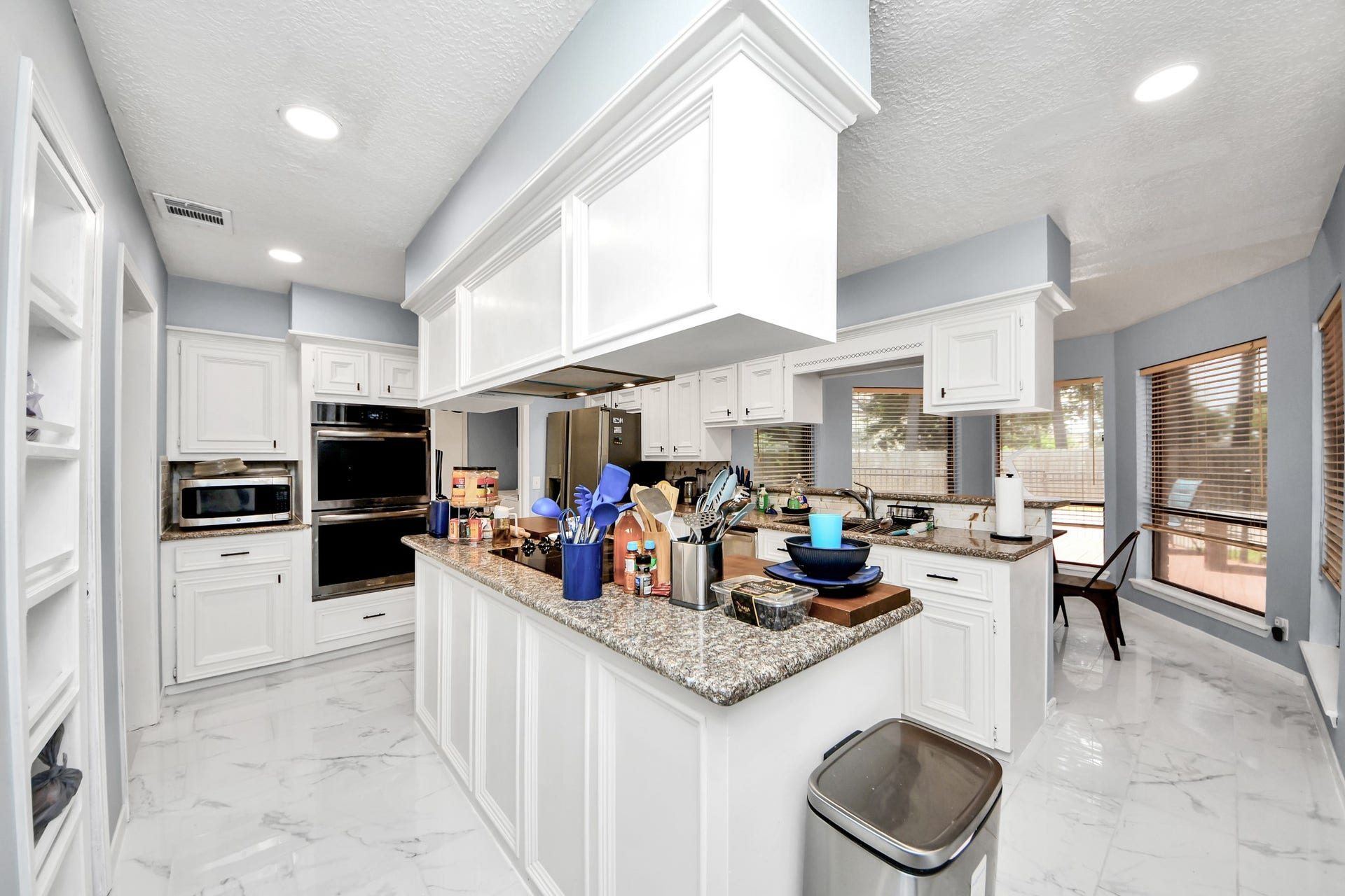2903 Blue Glen Lane, Houston, TX 77073 A chefs dream configuration. Bright white cabinetry lines the kitchen to offer abundant storage, centered around an island cooktop and a raised breakfast bar that overlooks the neighboring breakfast area.
