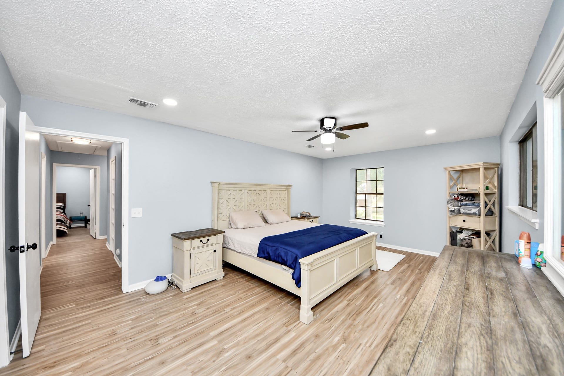 2903 Blue Glen Lane, Houston, TX 77073 Located for premium seclusion, this spacious primary bedroom pairs a cooling ceiling fan with broad windows that bathe the room in peaceful morning light.
