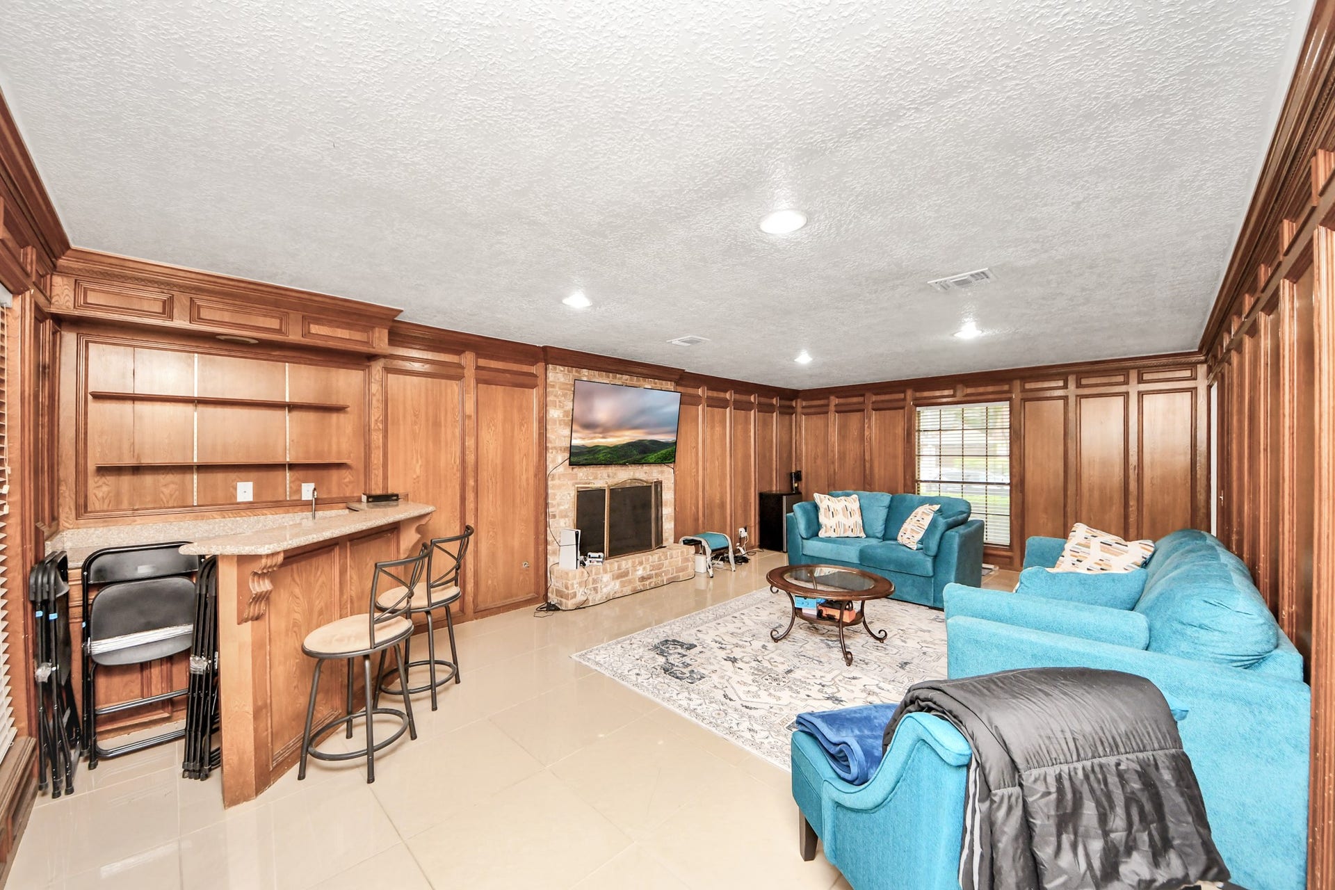 2903 Blue Glen Lane, Houston, TX 77073 Mid-century warmth meets modern luxury. Gorgeous, rich wood paneling anchors this magnificent living room, dynamically equipped with a dedicated wet bar, a central fireplace, and oversized windows.