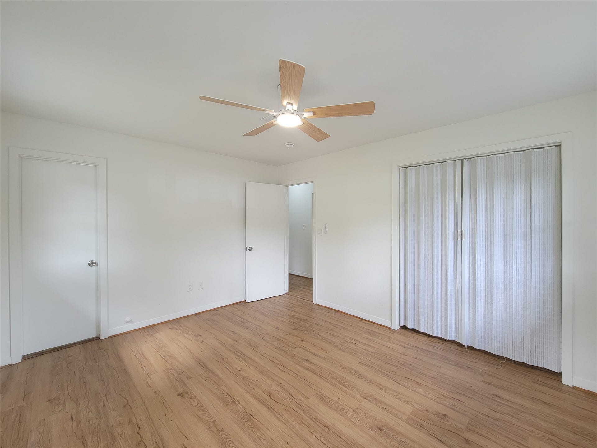 2605 W Dumble Street, Alvin, TX 77511 Discover a spacious bedroom with elegant wood flooring, a ceiling fan, and ample closet space with sliding doors, perfect for comfort and style.