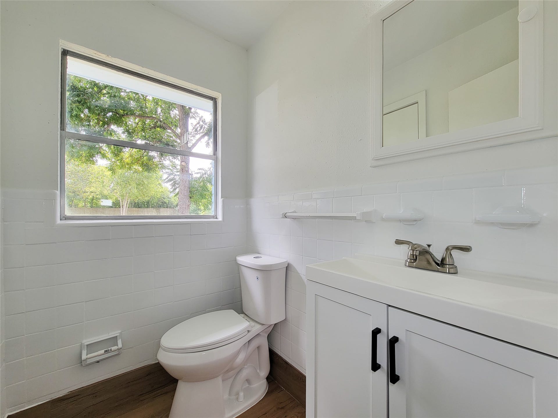 2605 W Dumble Street, Alvin, TX 77511 Experience tranquility in this bright and airy bathroom, boasting a large window with serene views, modern white fixtures, and sleek tile accents.
