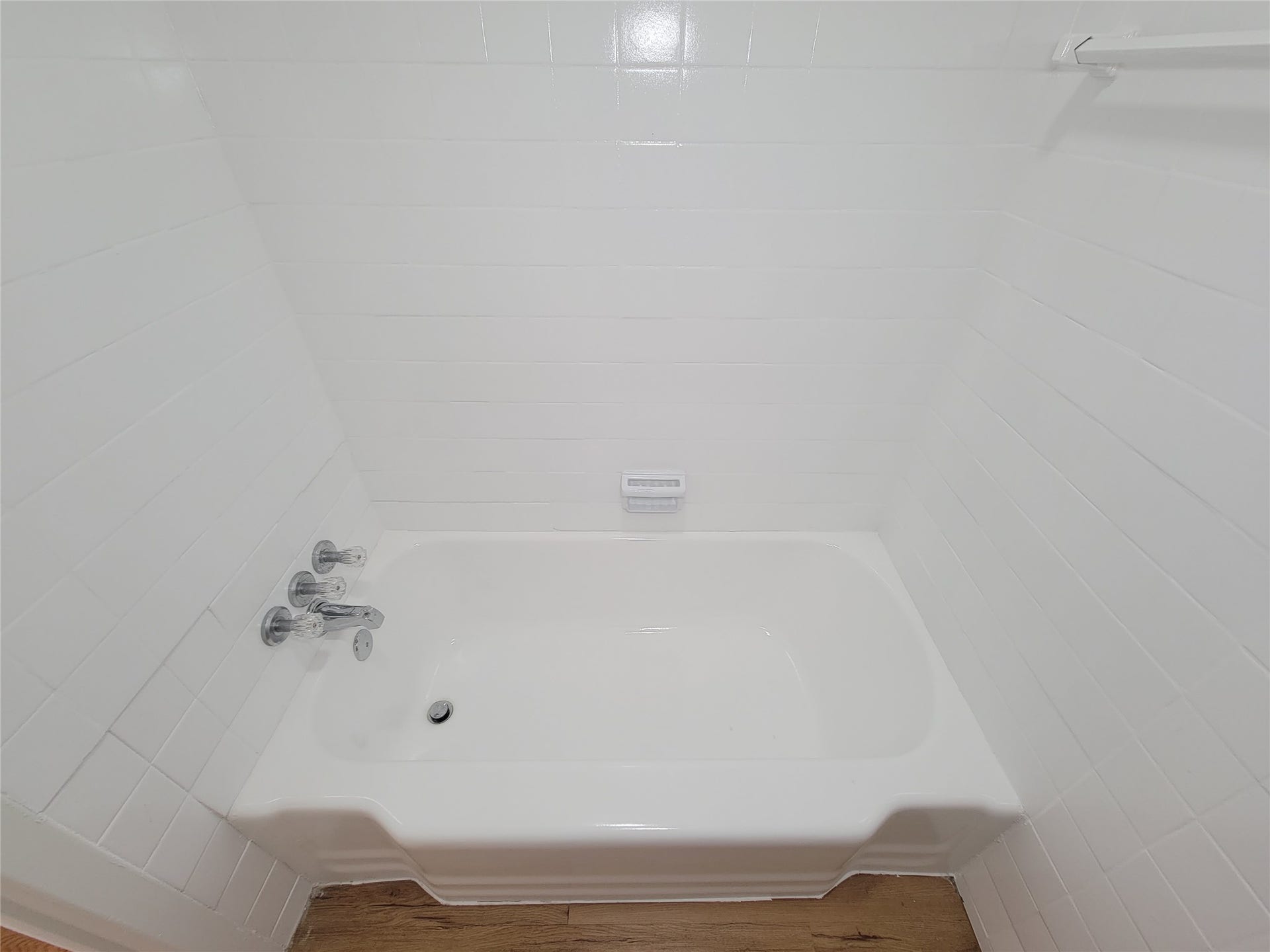 2605 W Dumble Street, Alvin, TX 77511 Experience a touch of elegance with this pristine white bathtub, featuring classic chrome fixtures set against sleek, white tile walls.