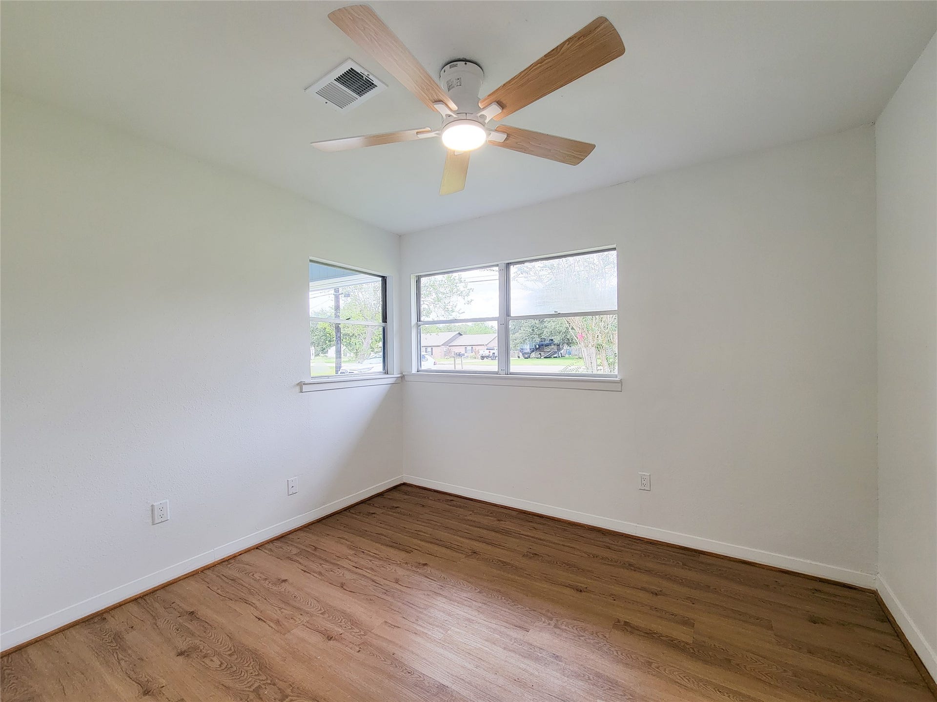 2605 W Dumble Street, Alvin, TX 77511 Experience the warmth of this bright and inviting bedroom, featuring large windows, elegant hardwood floors, and a sleek modern ceiling fan.
