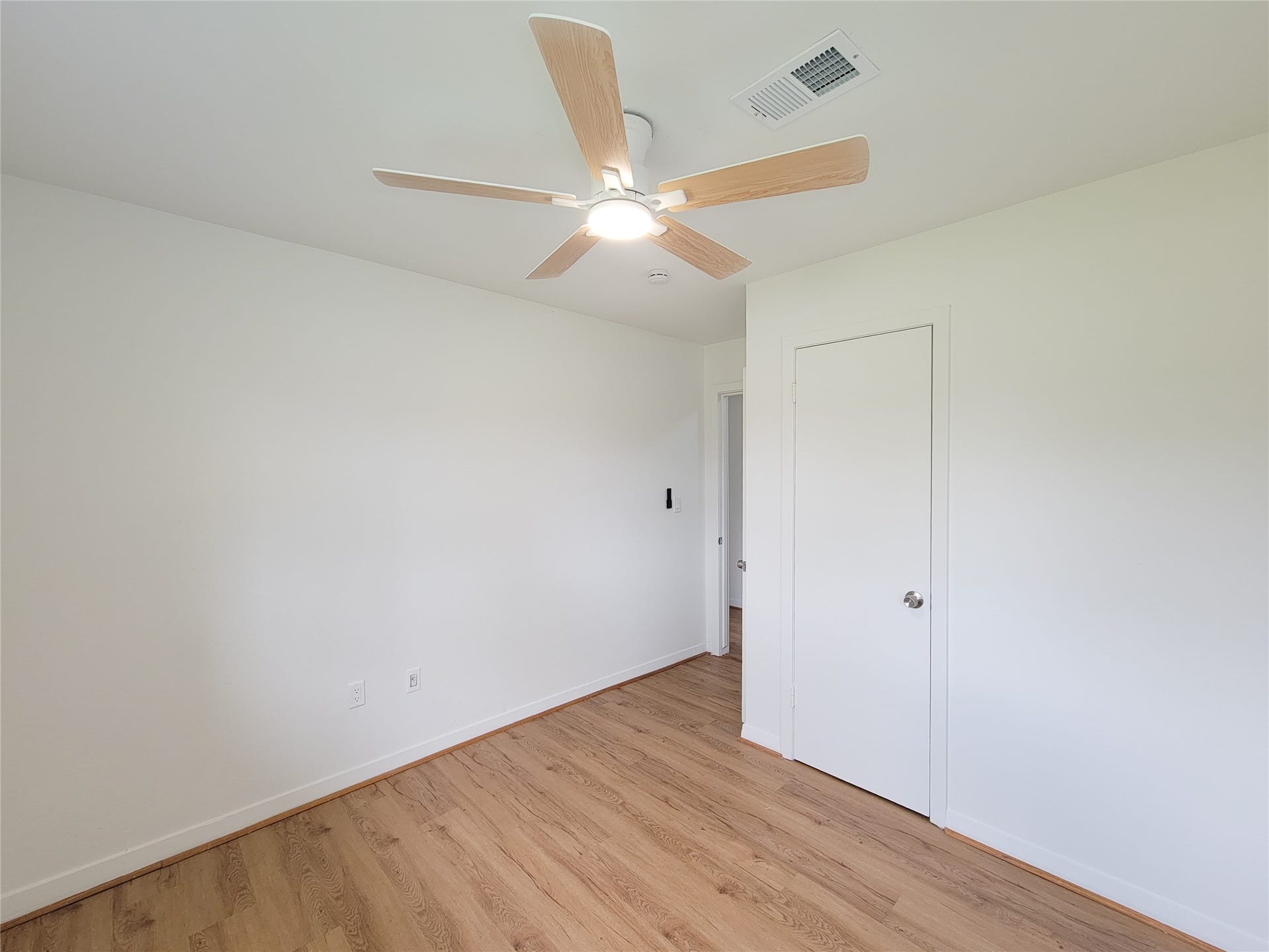 2605 W Dumble Street, Alvin, TX 77511 Experience the perfect blend of style and comfort in this bright and airy bedroom, featuring fresh white walls, warm wood flooring, and a sleek modern ceiling fan.