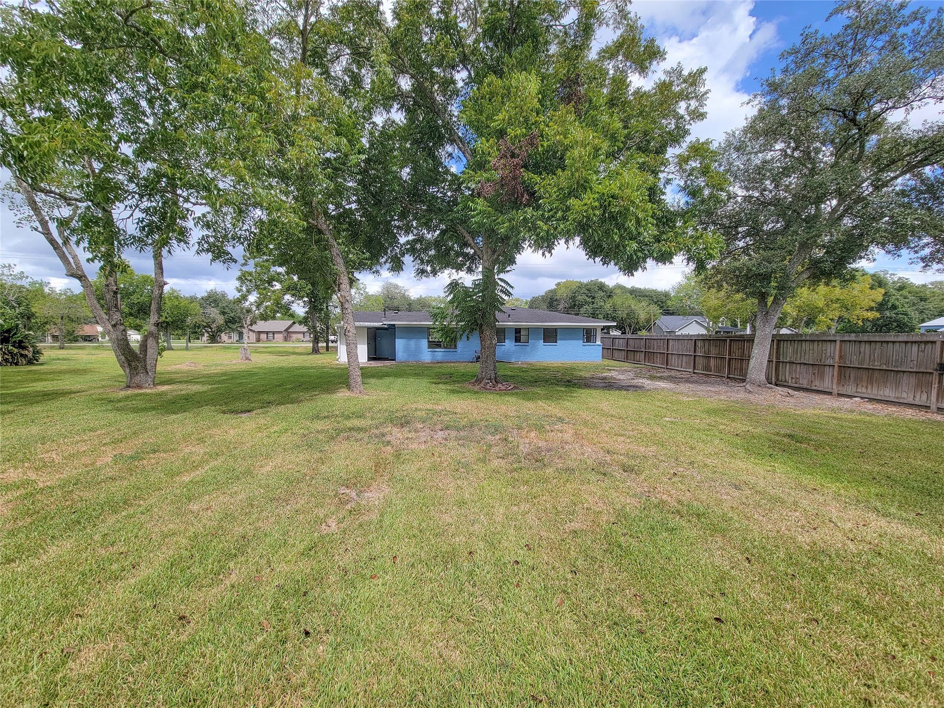 2605 W Dumble Street, Alvin, TX 77511 Discover a serene oasis with an expansive backyard featuring a lush green lawn and mature trees, perfect for outdoor activities and relaxation.