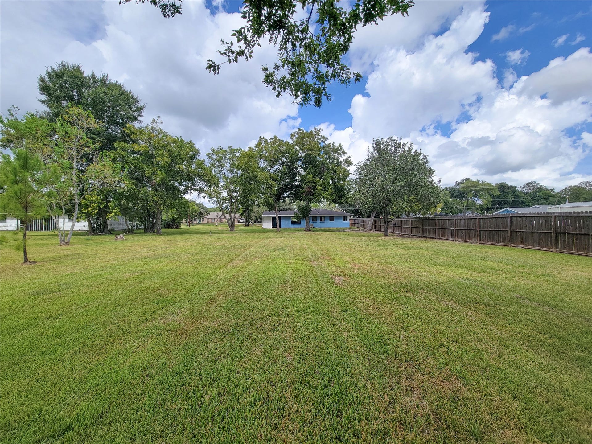 2605 W Dumble Street, Alvin, TX 77511 Discover an expansive, lush backyard adorned with mature trees, offering ample space for outdoor activities, perfect for embracing nature and entertaining guests.