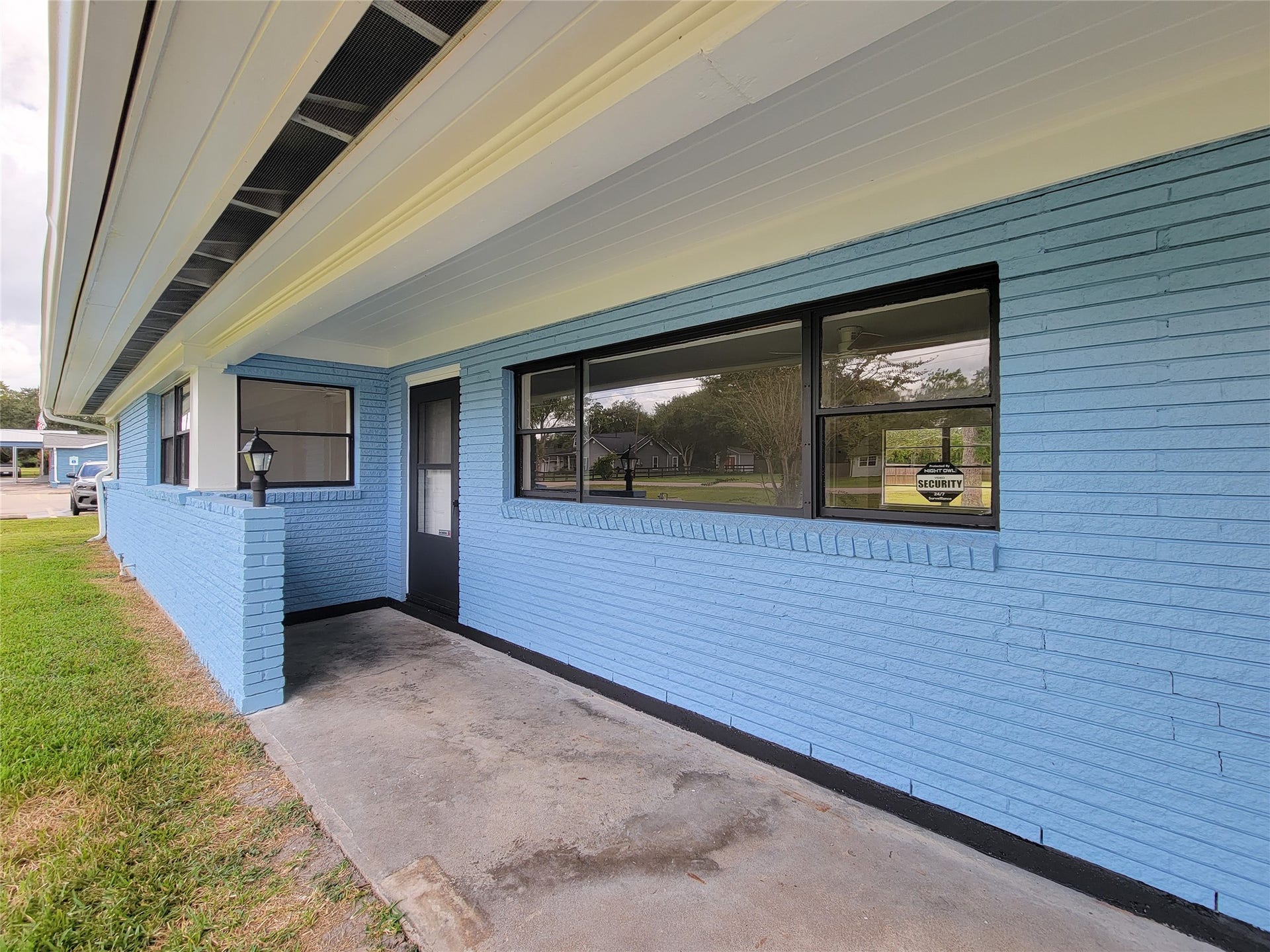 2605 W Dumble Street, Alvin, TX 77511 Charming blue brick exterior with a welcoming covered front porch and large windows, ideal for enjoying the outdoors.