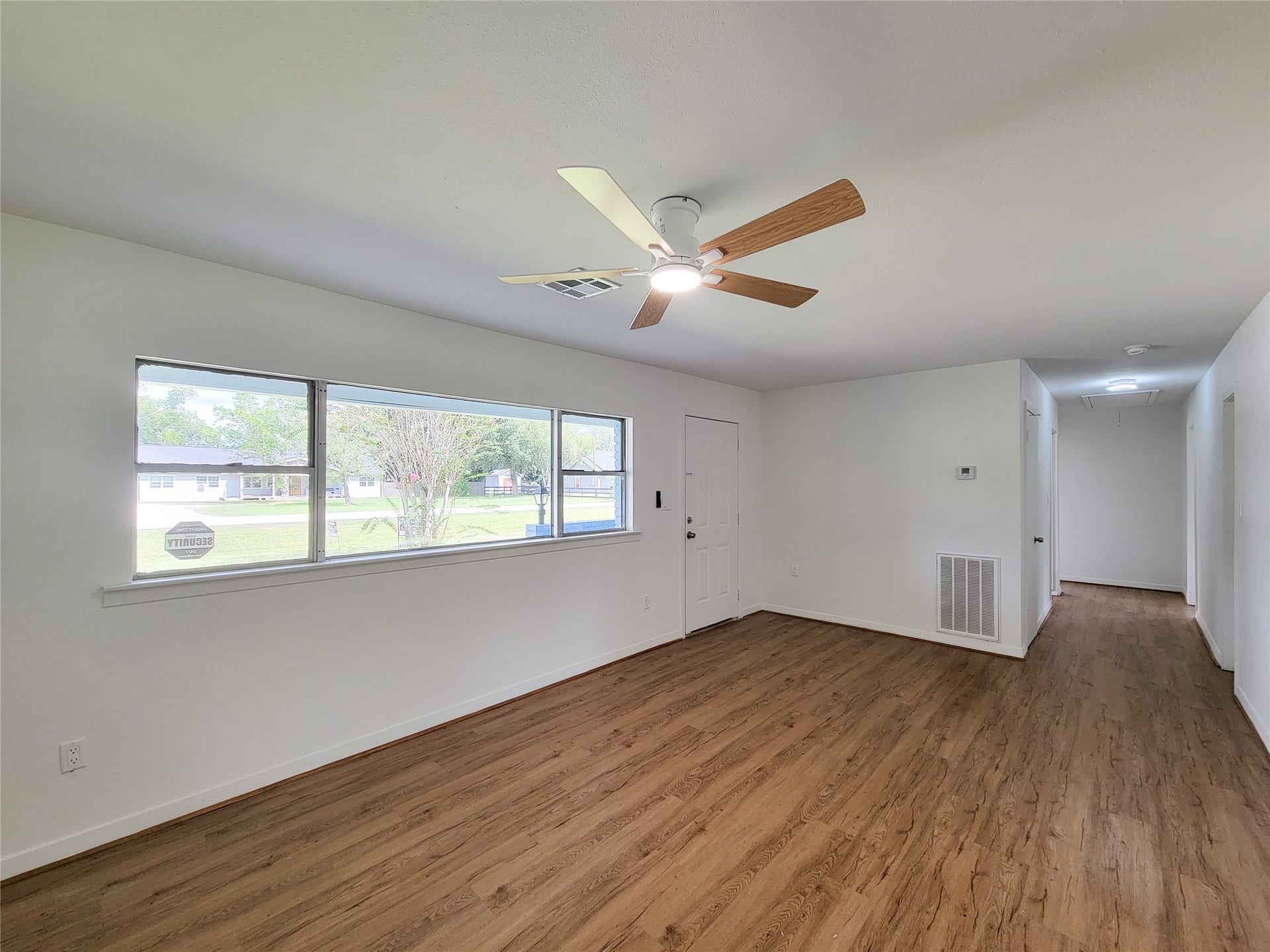 2605 W Dumble Street, Alvin, TX 77511 Experience a bright and inviting living space with large windows, sleek wood flooring, and a modern ceiling fan, perfect for creating a welcoming atmosphere.