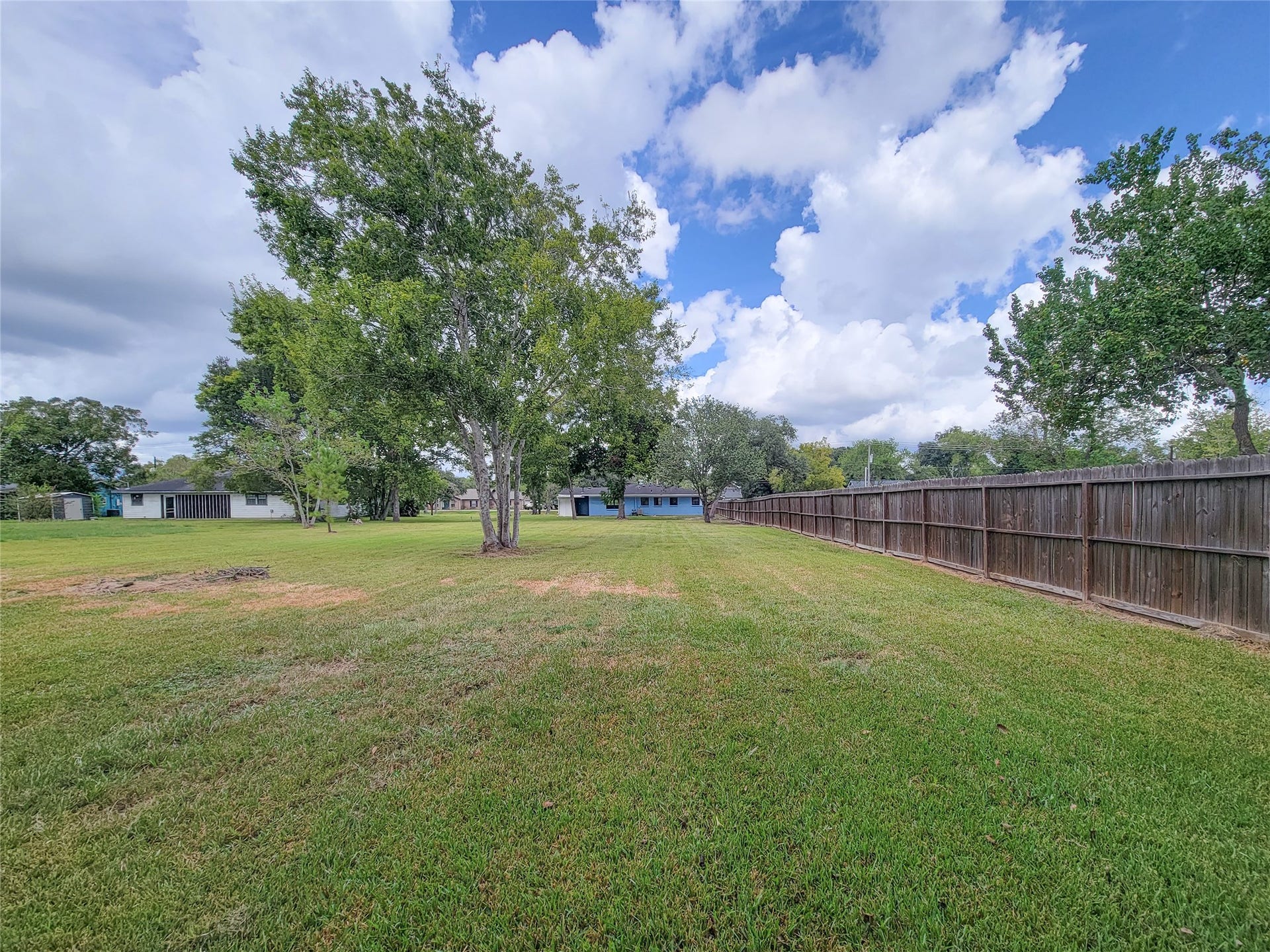 2605 W Dumble Street, Alvin, TX 77511 Discover an expansive, lush backyard with mature trees and a privacy fence, perfect for outdoor activities and tranquil relaxation.