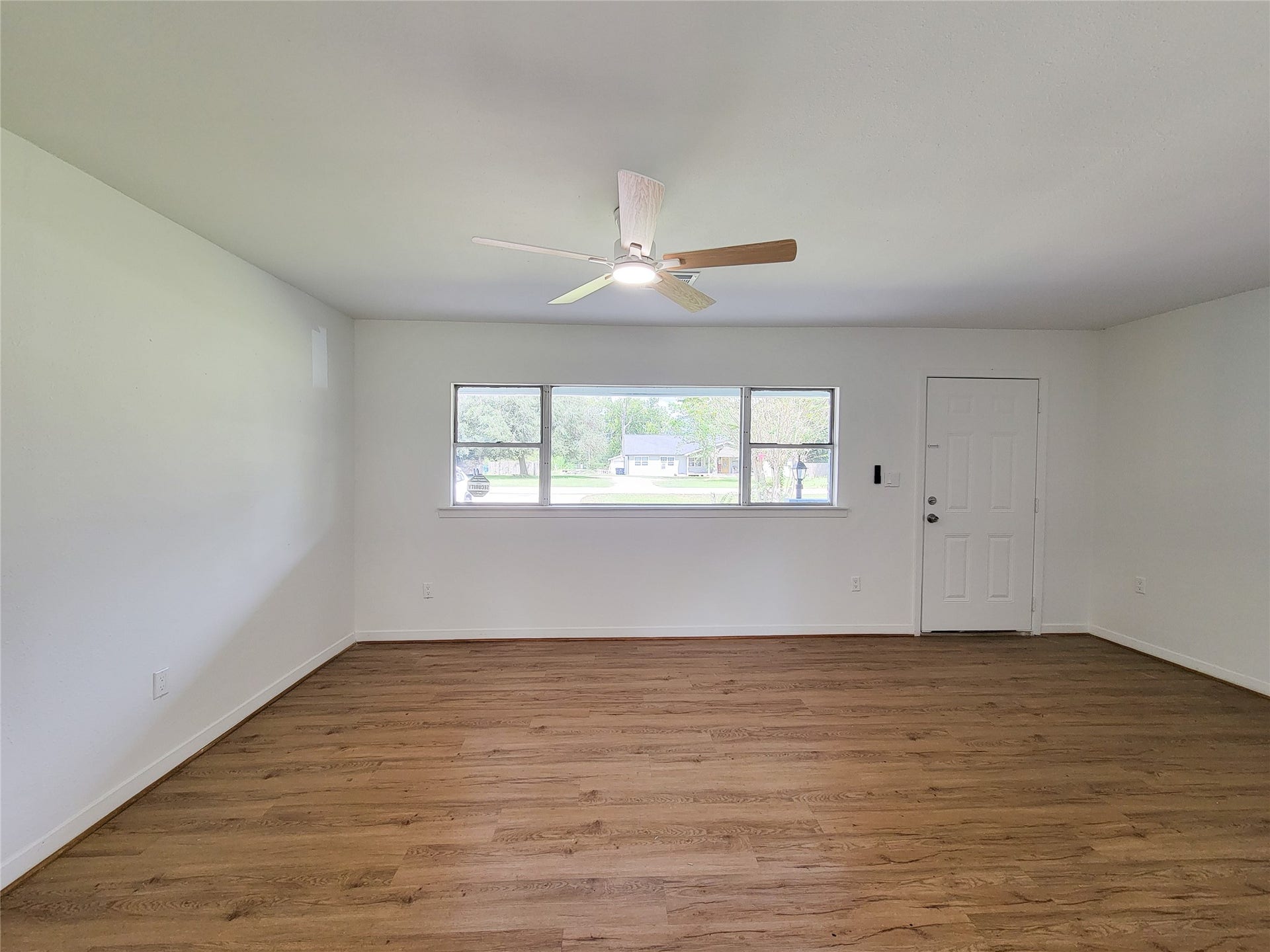 2605 W Dumble Street, Alvin, TX 77511 Bright and airy living space with large windows, sleek hardwood flooring, and a modern ceiling fan, creating a welcoming and comfortable ambiance.