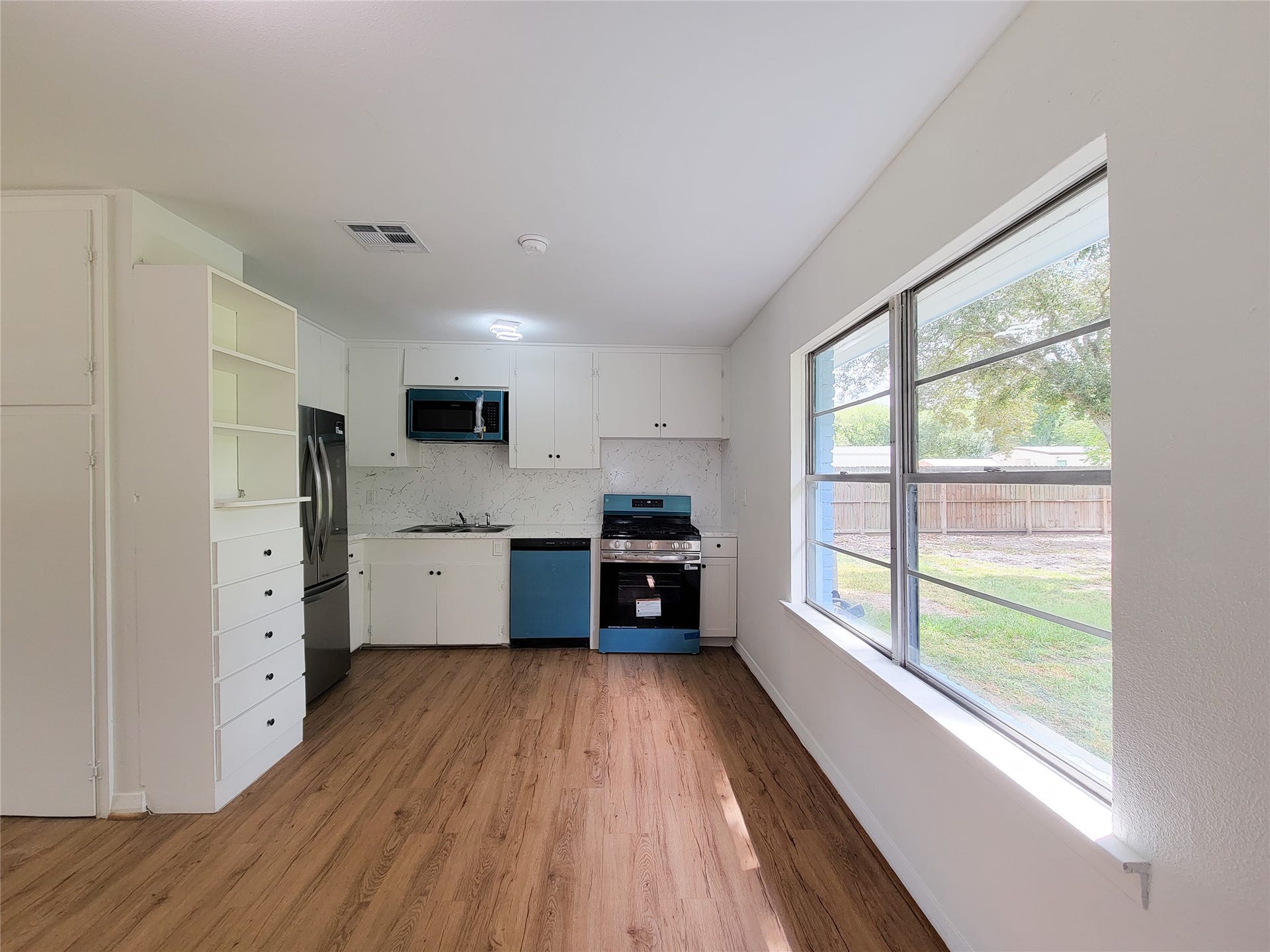 2605 W Dumble Street, Alvin, TX 77511 Experience a bright kitchen with modern stainless steel appliances, ample cabinetry, and large windows offering serene backyard views.