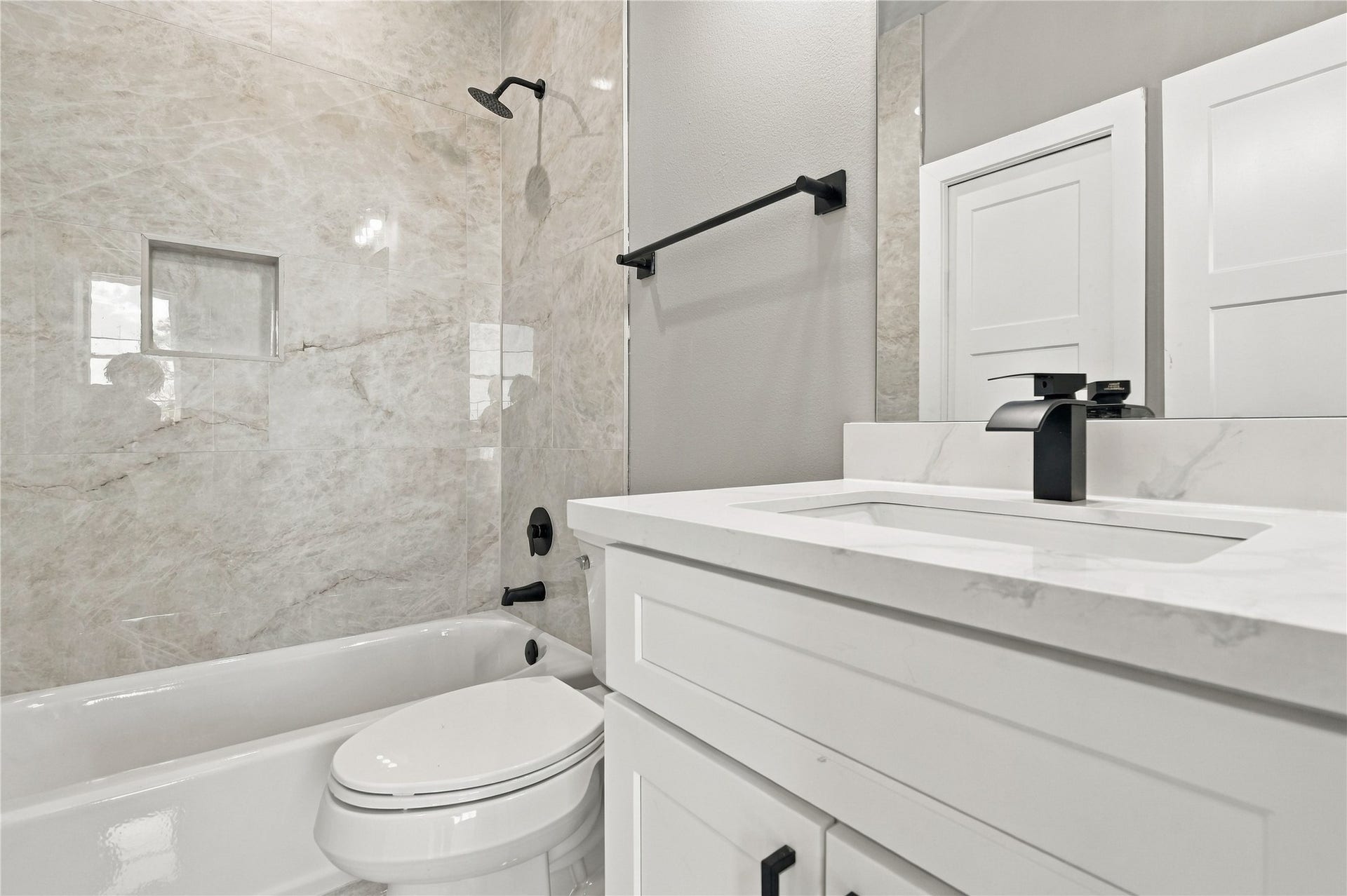 4313 Clover Street, #A/B, Houston, TX 77051 Modern bathroom featuring sleek marble tiles, a stylish black faucet, and a spacious vanity with ample storage.