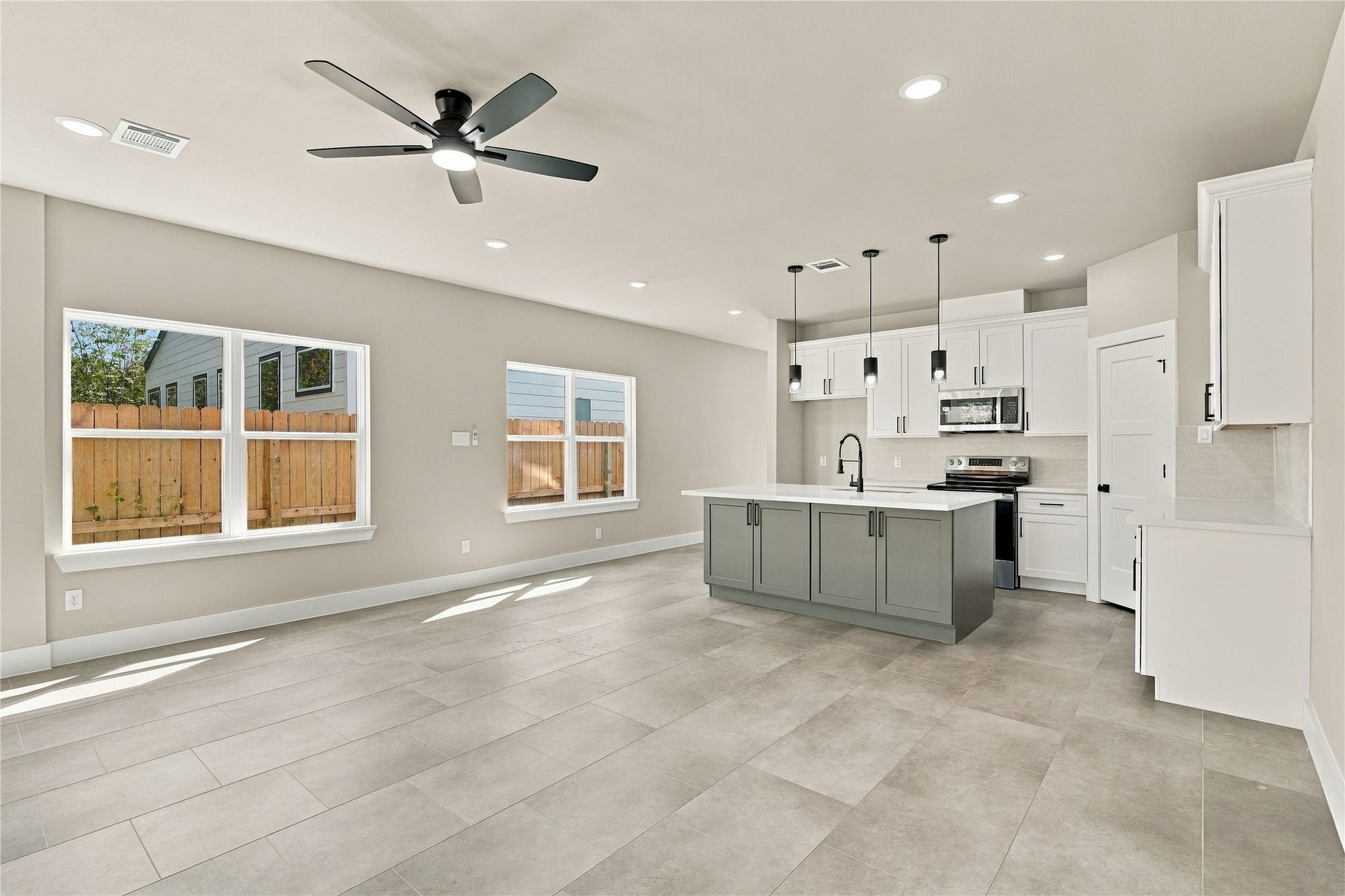 4313 Clover Street, #A/B, Houston, TX 77051 Bright and spacious open-concept living area featuring a modern kitchen with a large island, sleek cabinetry, and stainless steel appliances, complemented by elegant tile flooring and ample natural light.