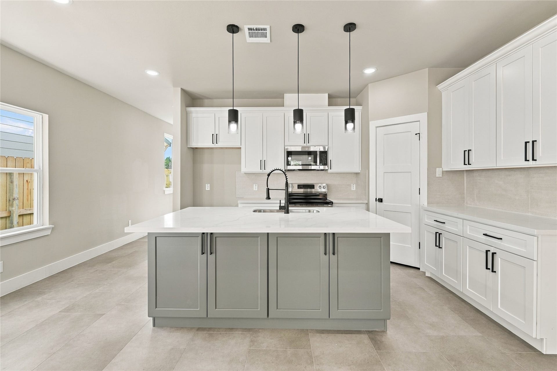 4313 Clover Street, #A/B, Houston, TX 77051 Bright and modern kitchen featuring a spacious island with a sleek quartz countertop, contemporary pendant lighting, and ample cabinetry in a stylish neutral palette.